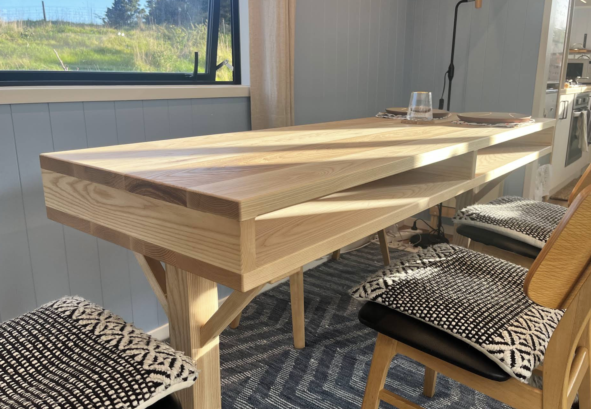 Custom Macrocarpa indoor dining table with built-in storage made for a tiny house.