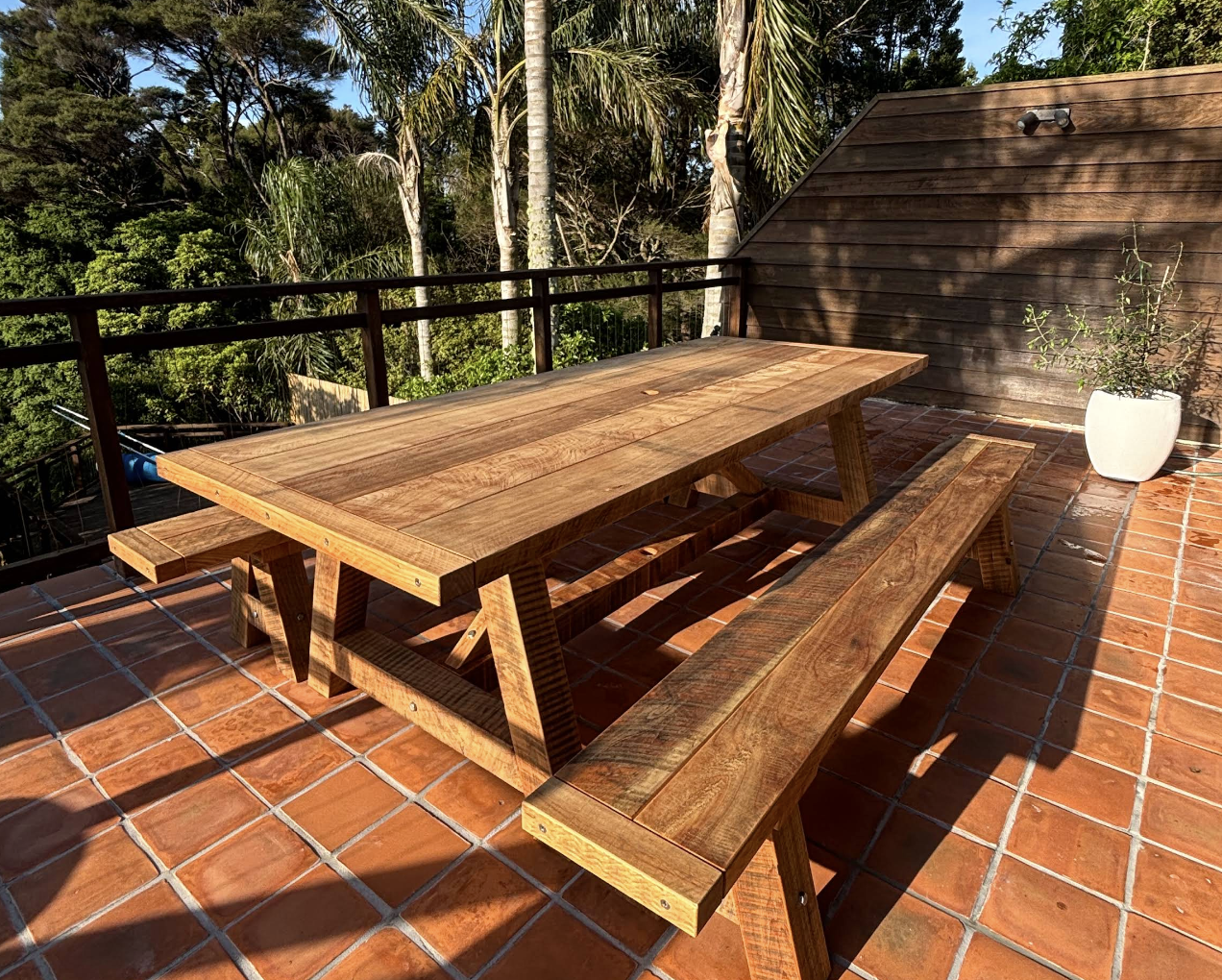 Macrocarpa dining table with matching bench seats in a customer’s outdoor living area.