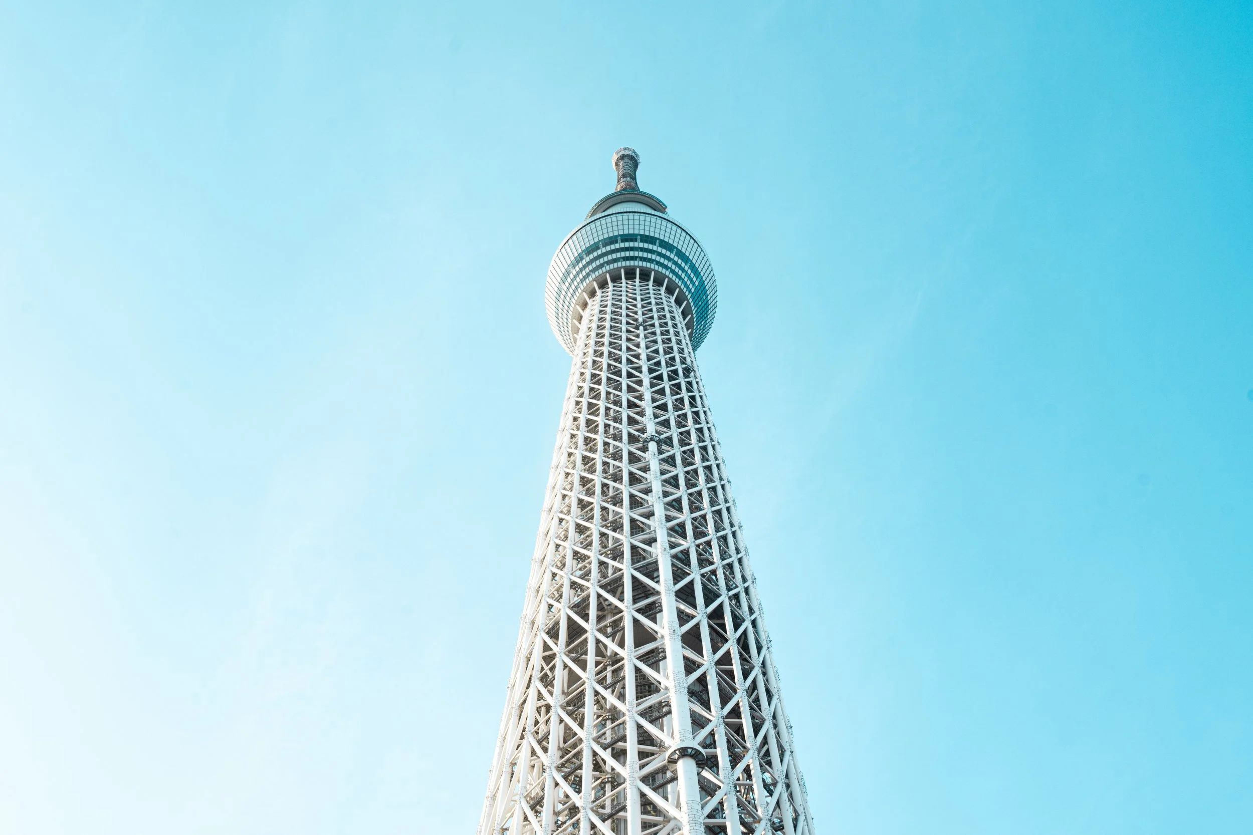 A tall, modern tower with a lattice structure and an observation deck near the top, set against a clear blue sky.
