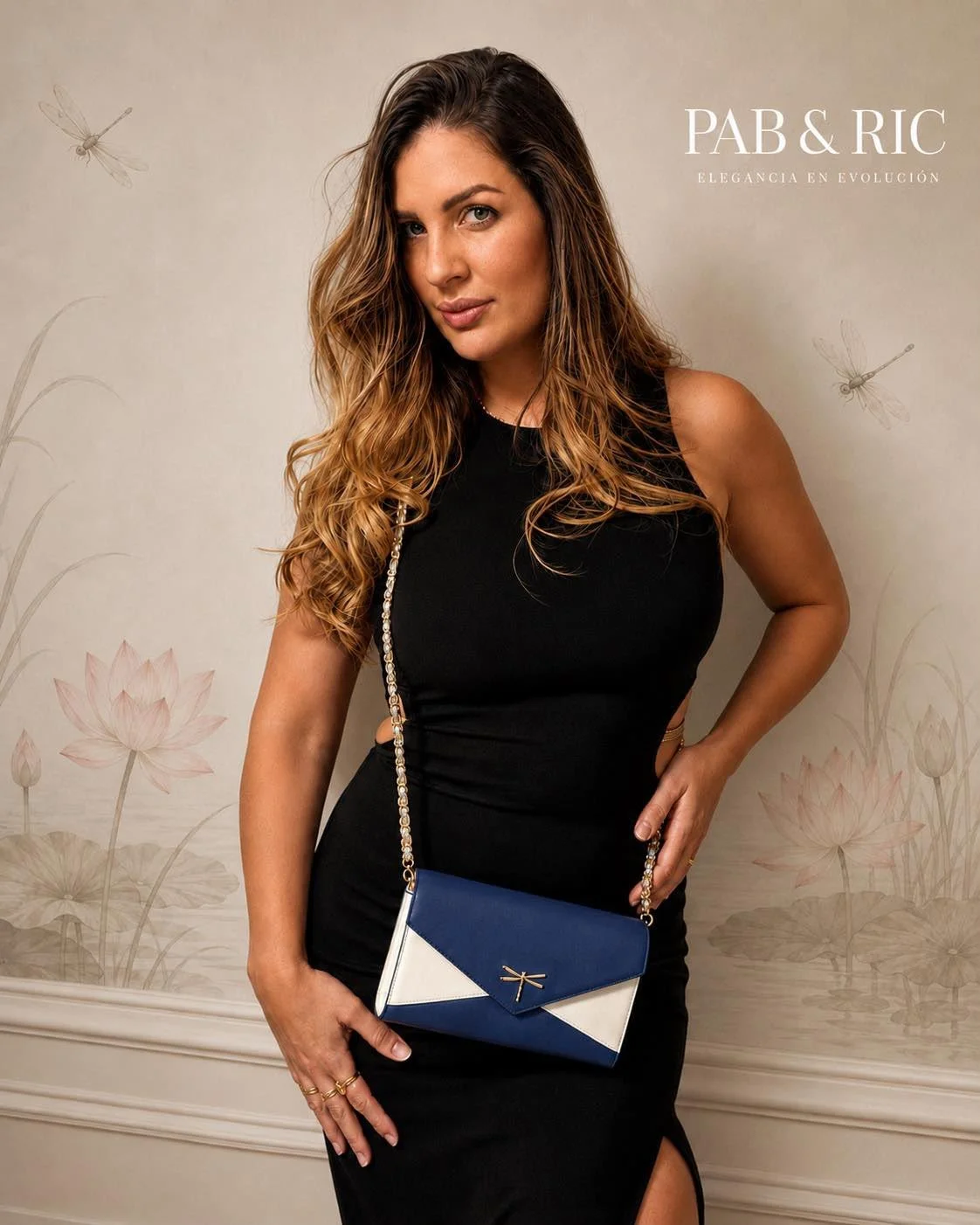 Mujer con cabello rizado y largo, con vestido negro y bolso azul y blanco, posando frente a un fondo con ilustraciones de nenúfares y libélulas.