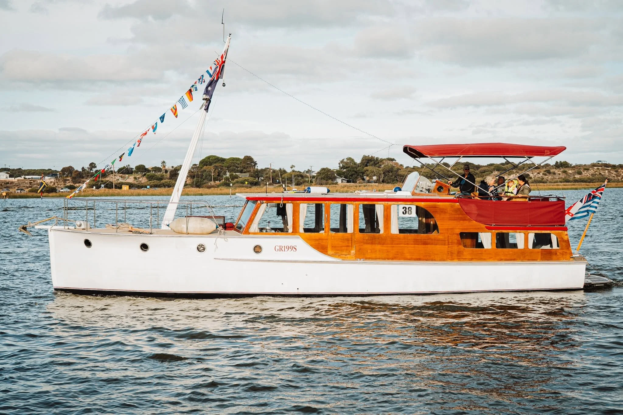 A wooden boat with a red canopy and a white hull, decorated with nautical flags.