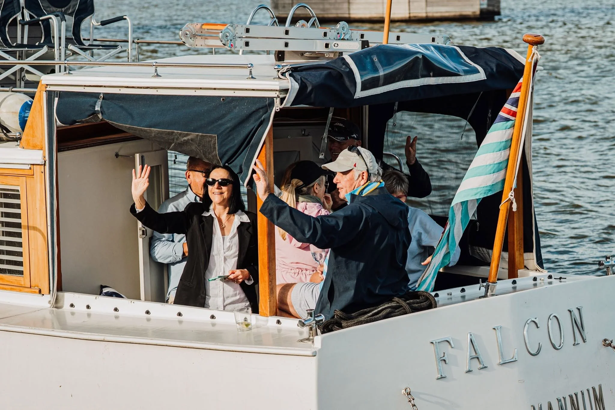A group of people on a boat enjoying a boat cruise, with some waving and smiling. 
