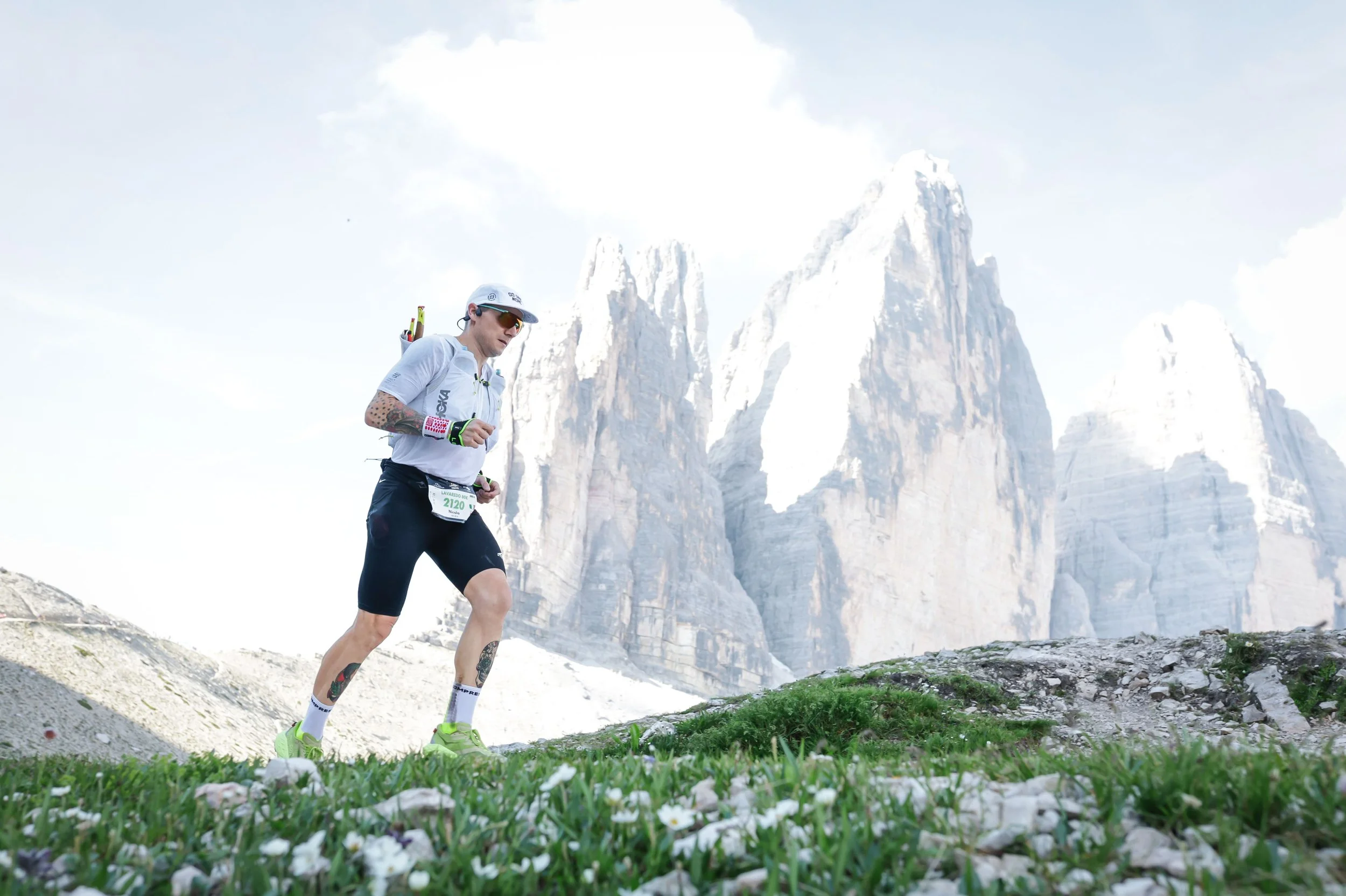 Uomo che corre in montagna con montagne e cielo nuvoloso sullo sfondo.