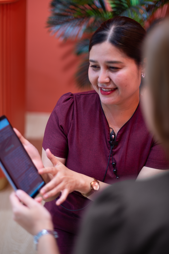 Smiling Ponsarin clinic staff member consulting with a client, reviewing information on a tablet.