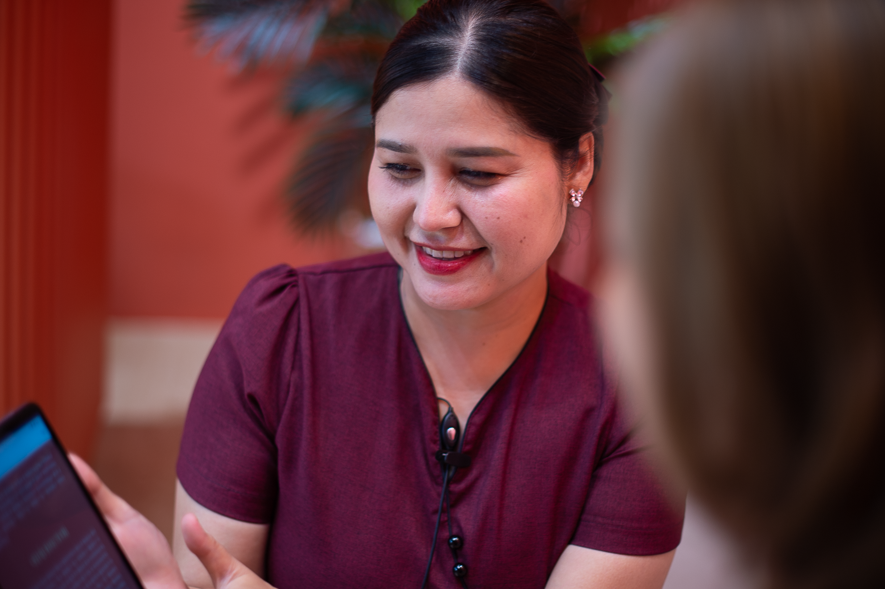 "Smiling Ponsarin Clinic receptionist helping a client select a treatment package on a tablet."