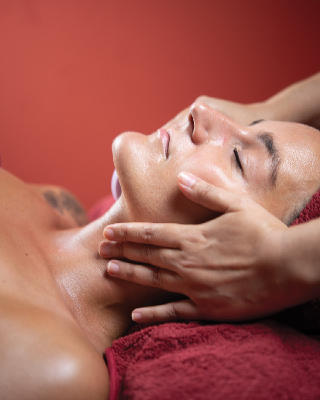 Person receiving a facial massage from a massage therapist in a spa setting.