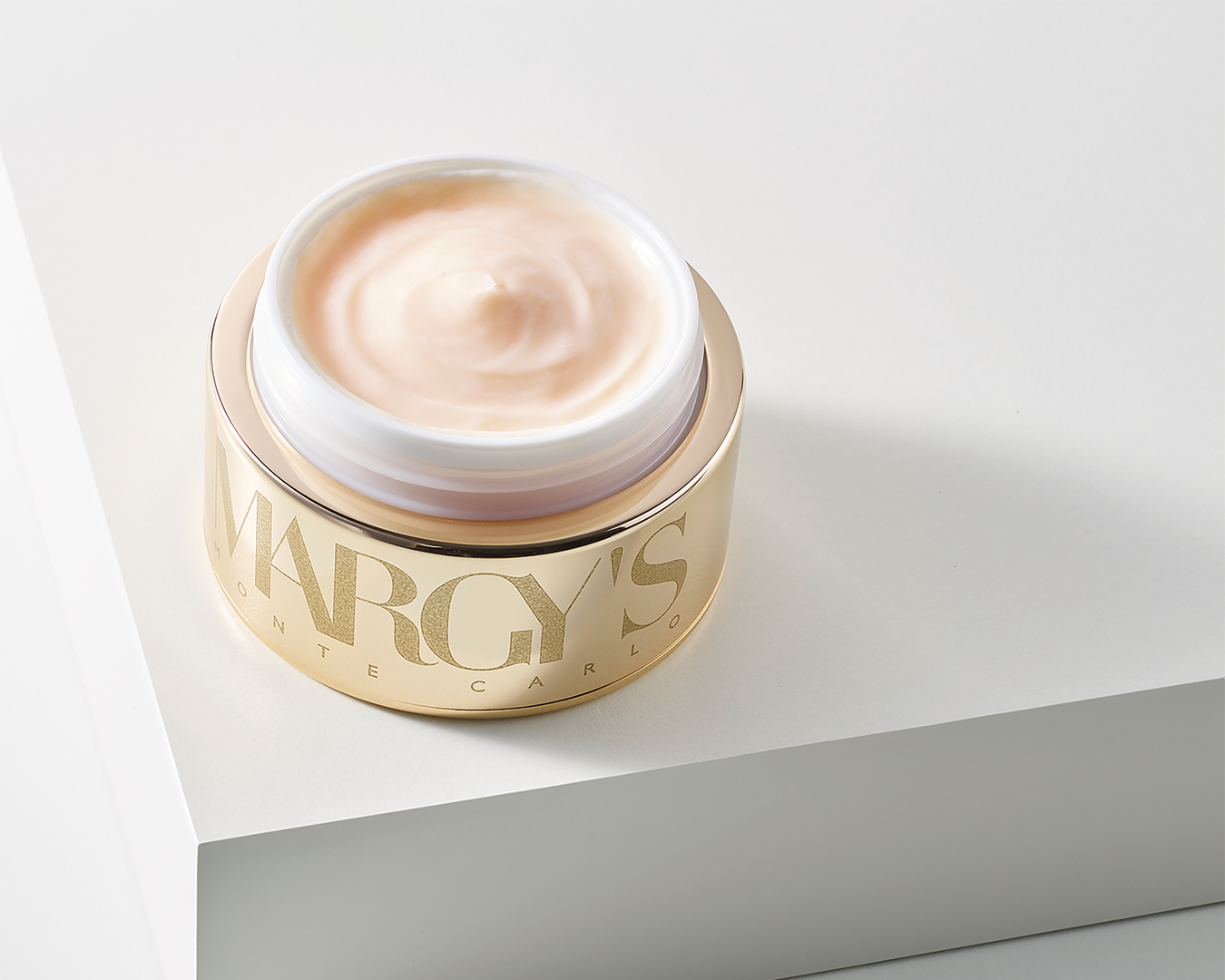 Open jar of Margy's skincare cream with cream-colored packaging and gold lettering, placed on a light gray surface.
