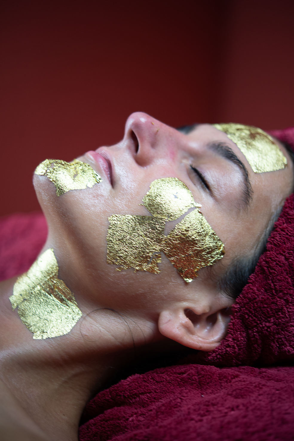 Client's face with gold flakes applied during a Ponsarin Clinic thermalift & gold facial treatment.