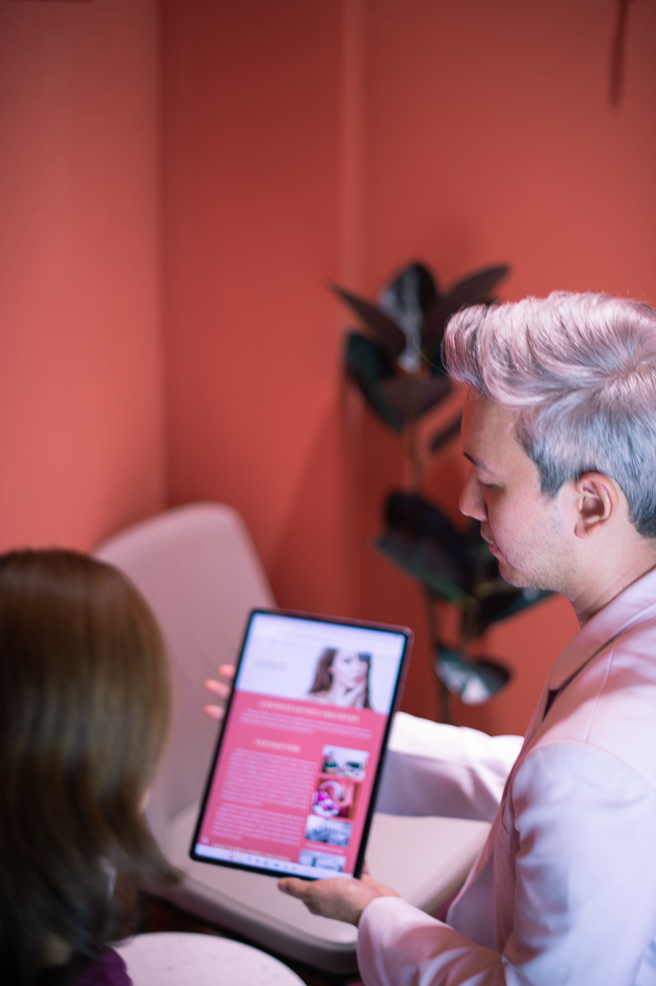 Ponsarin clinic doctor discussing an aesthetic treatment consultation with a client, reviewing details on a tablet.