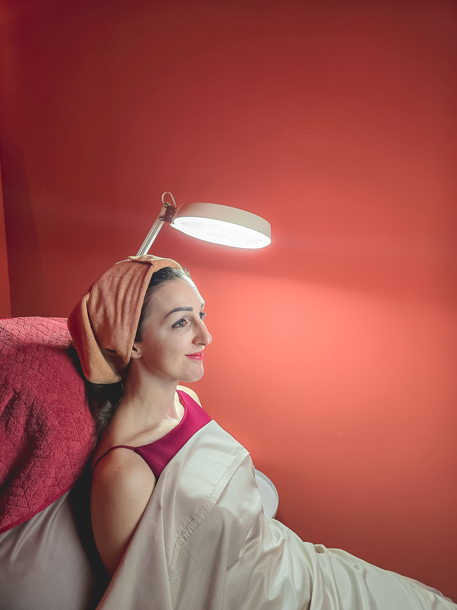 Client wearing a hair towel wrap seated under a magnifying lamp, waiting for an UltraLifted treatment at Ponsarin Clinic.