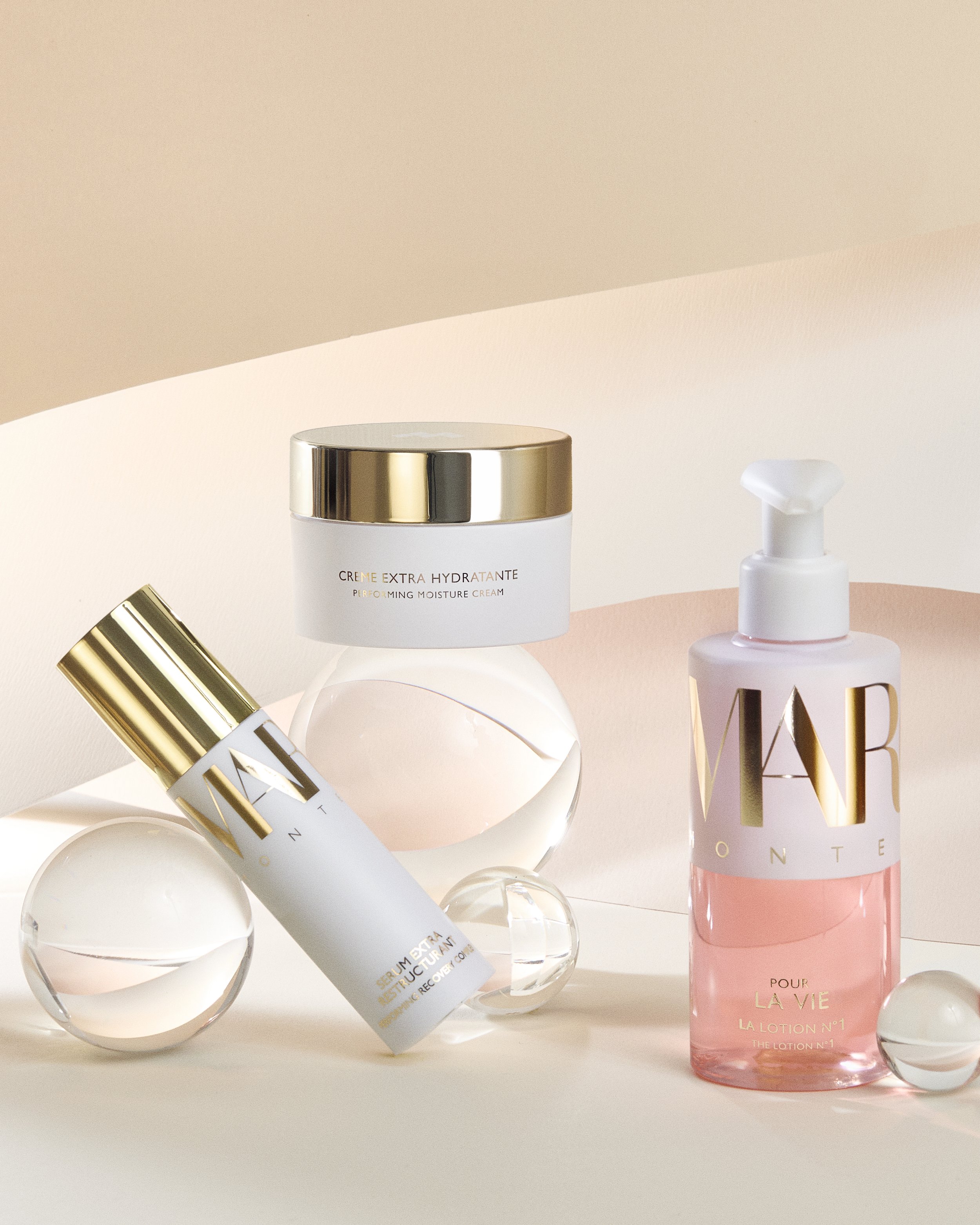 Margy's Monte Carlo Pour La Vie skincare range, featuring Crème Extra Hydratante moisture cream, a gold-capped serum tube, and a pink pump bottle.