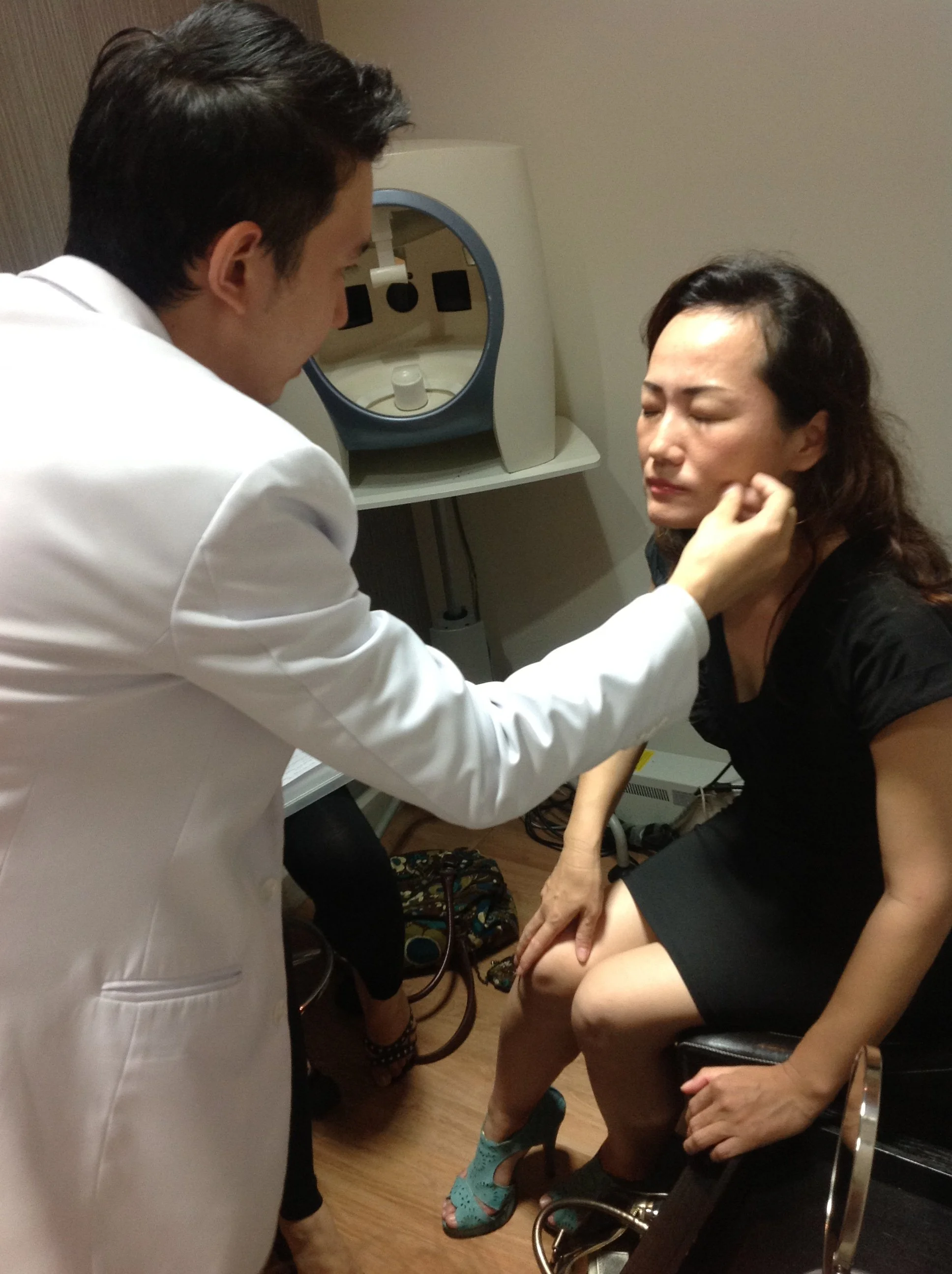 Doctor assessing a patient's facial contours during a PDO thread lift consultation at Ponsarin Clinic in Chiang Mai, Thailand.