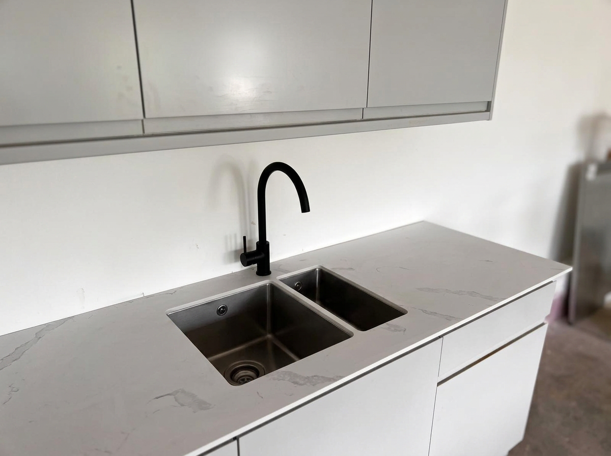 Modern kitchen countertop with a stainless-steel sink and a black faucet.