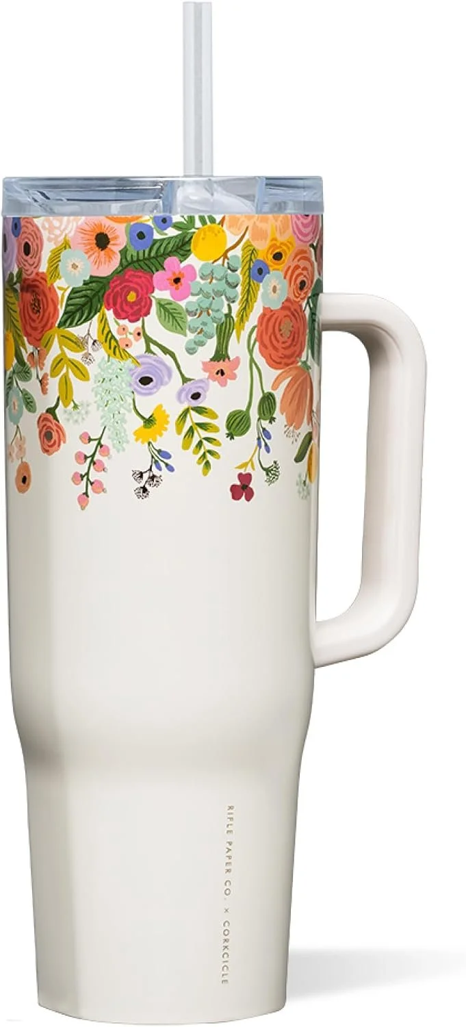 A reusable travel mug with a floral pattern near the top and a white handle, containing a drink with a straw.