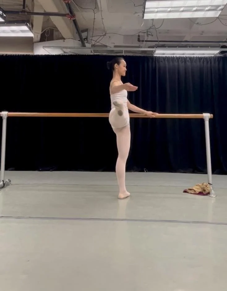 Ballet dancer practising at a home barre during online coaching.