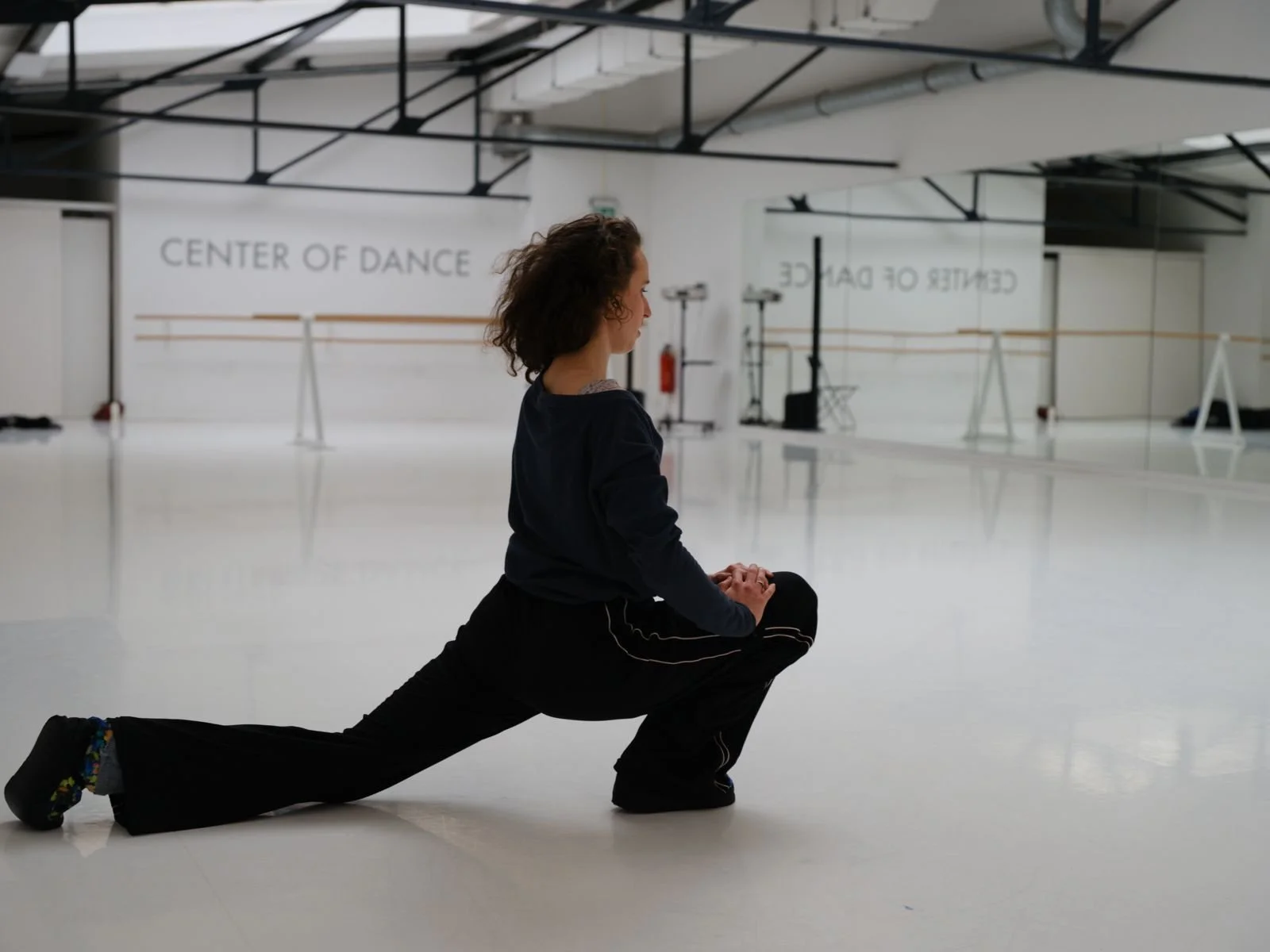 Dancer completing a floor-based conditioning stretch in a white studio.