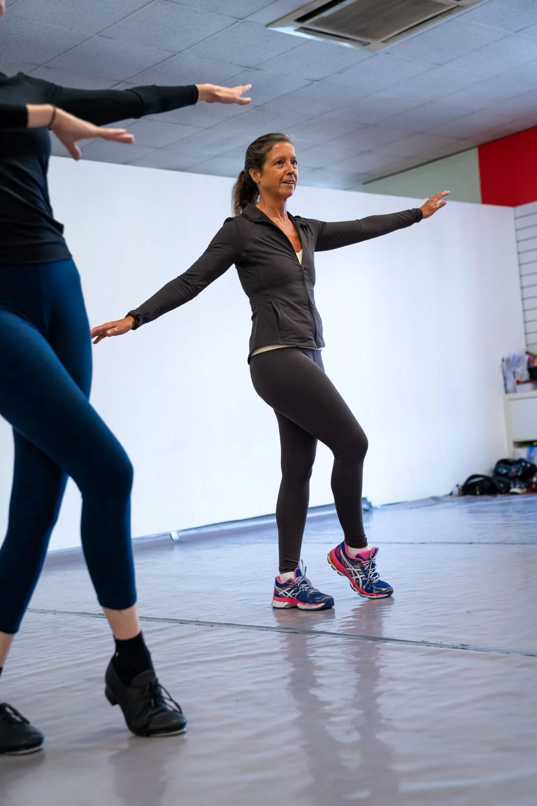 Adults taking part in a ballet conditioning class with arms extended.