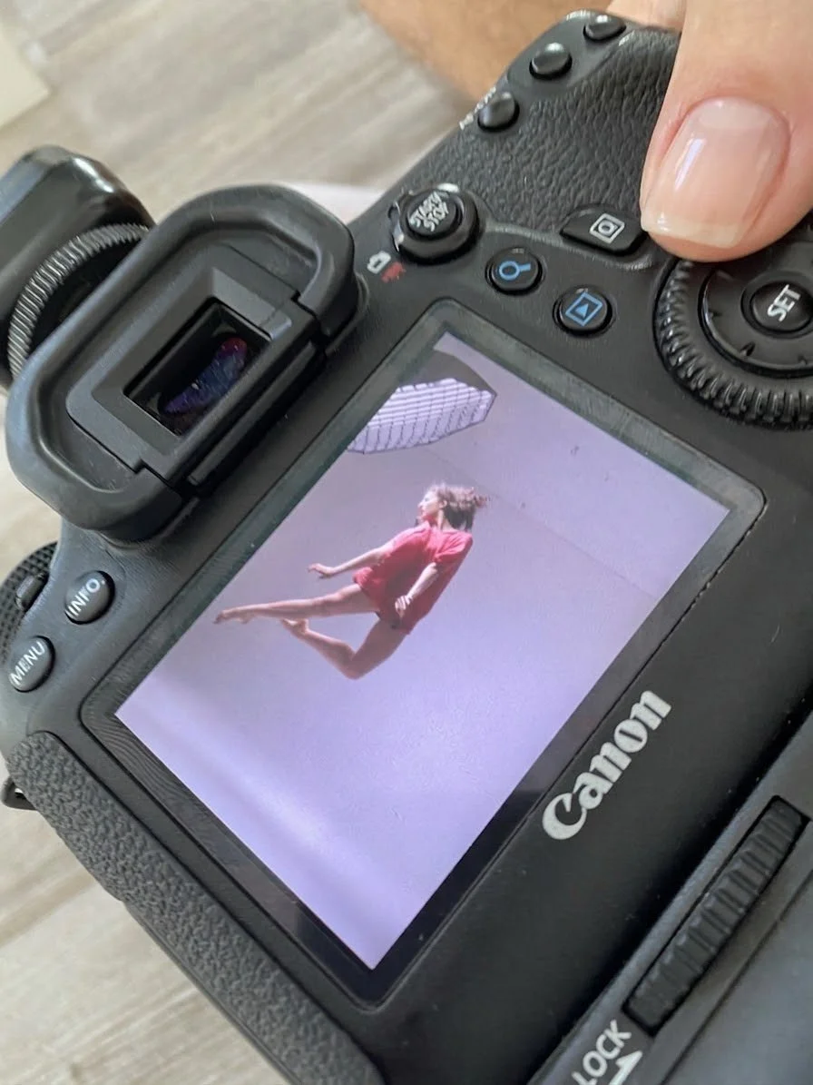 Camera screen showing a ballet dancer in a pink dress during an audition photoshoot.
