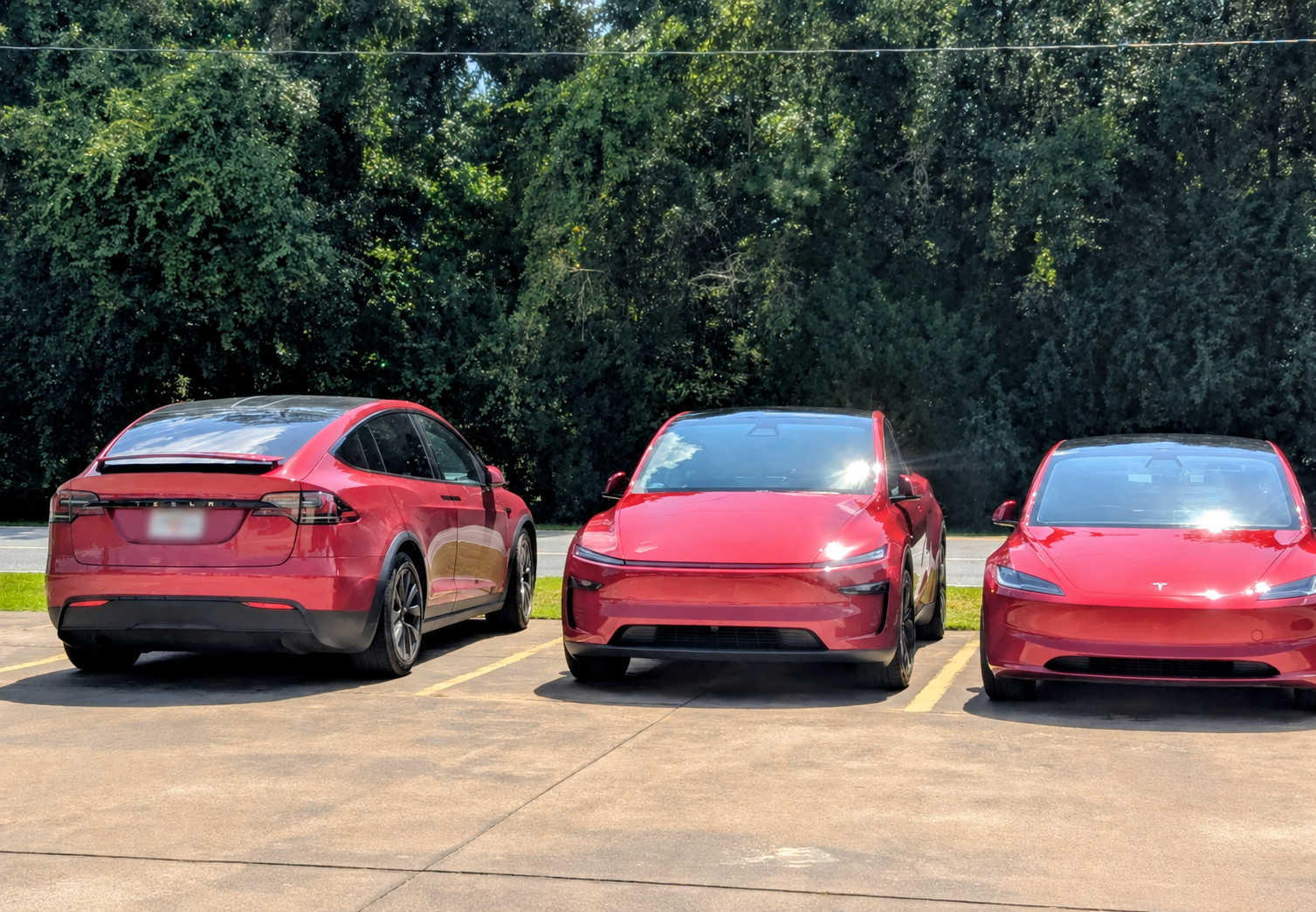Three red Tesla electric vehicles parked together during an EV road trip