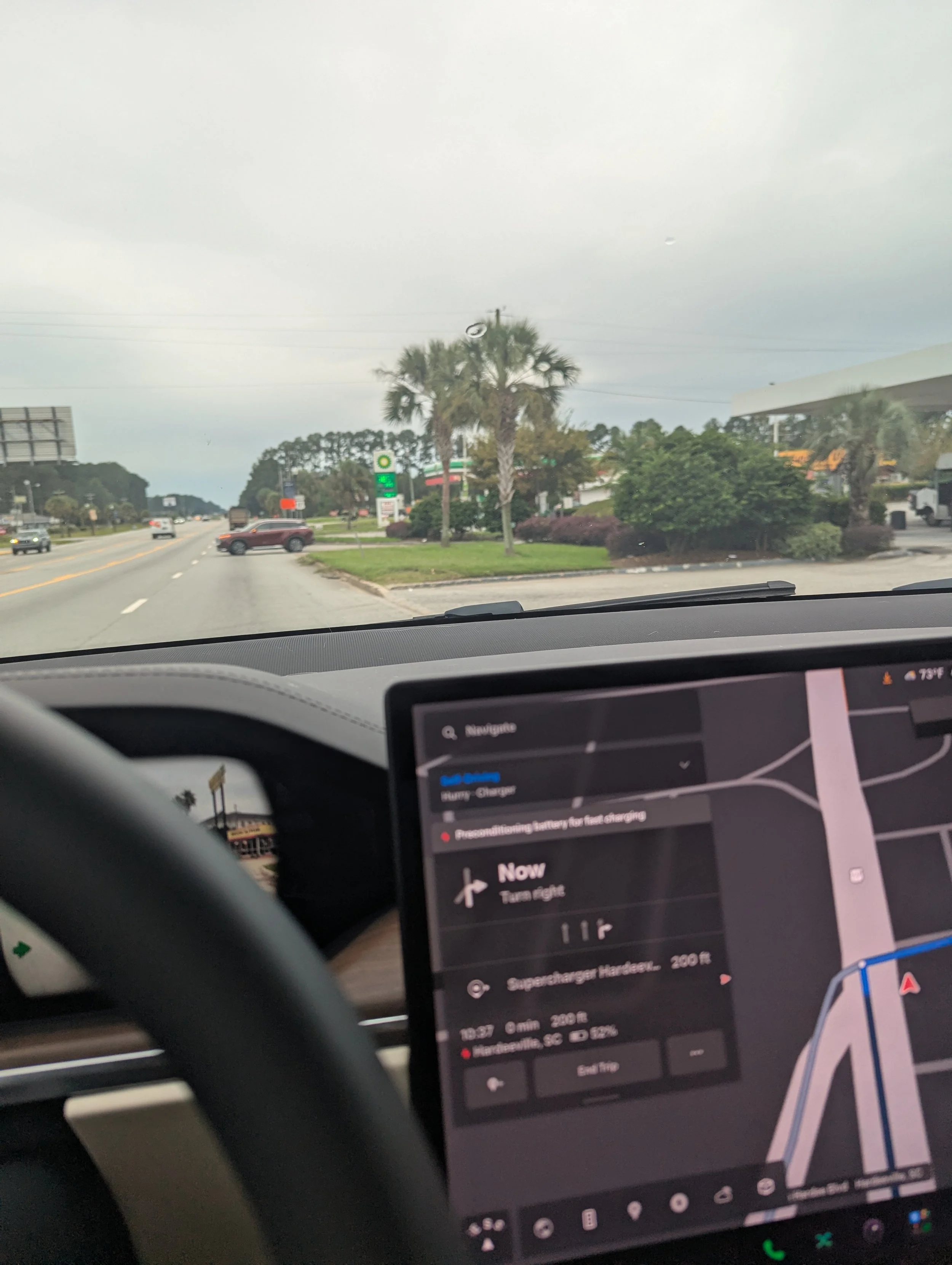 View through the windshield of our Tesla Model X approaching a Supercharger location in South Carolina, with the navigation screen displaying directions and battery preconditioning.