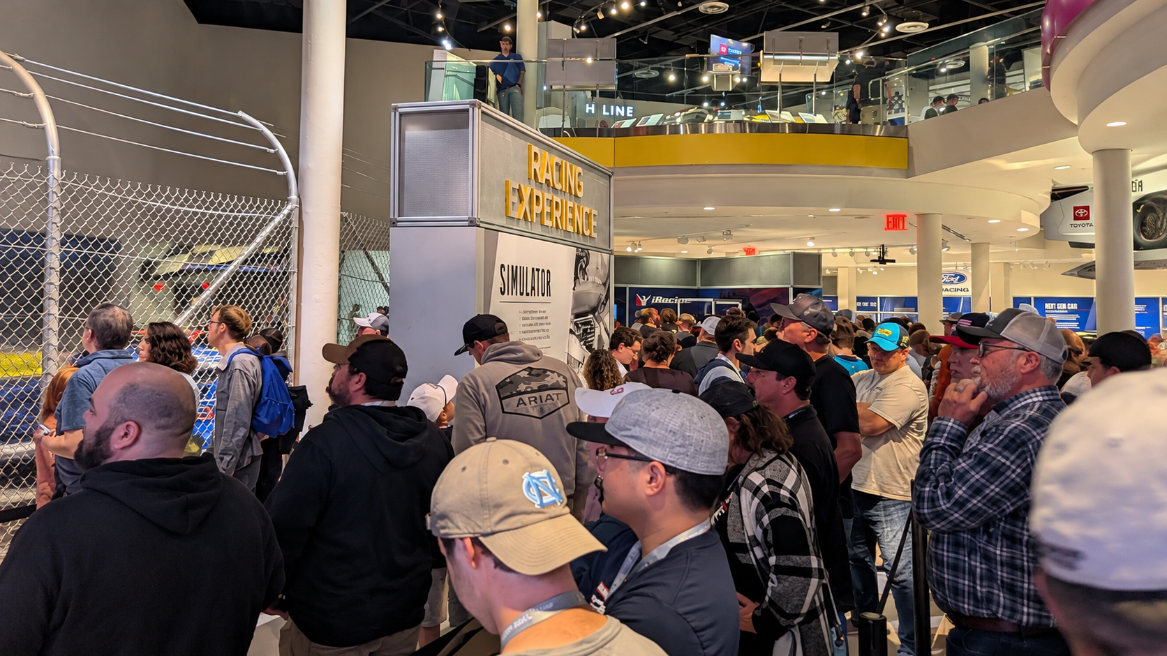 Visitors waiting in a crowded line for the NASCAR Hall of Fame racing simulator during a busy race weekend.