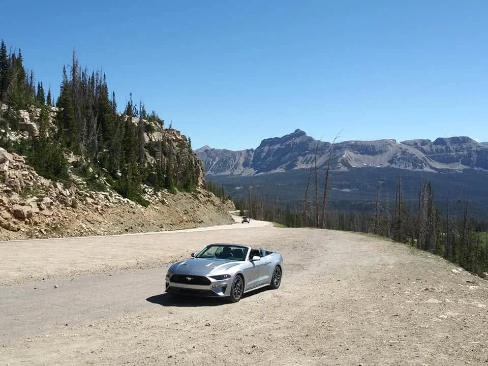 Silver convertible rental car parked along a mountain road during a summer trip through Utah.