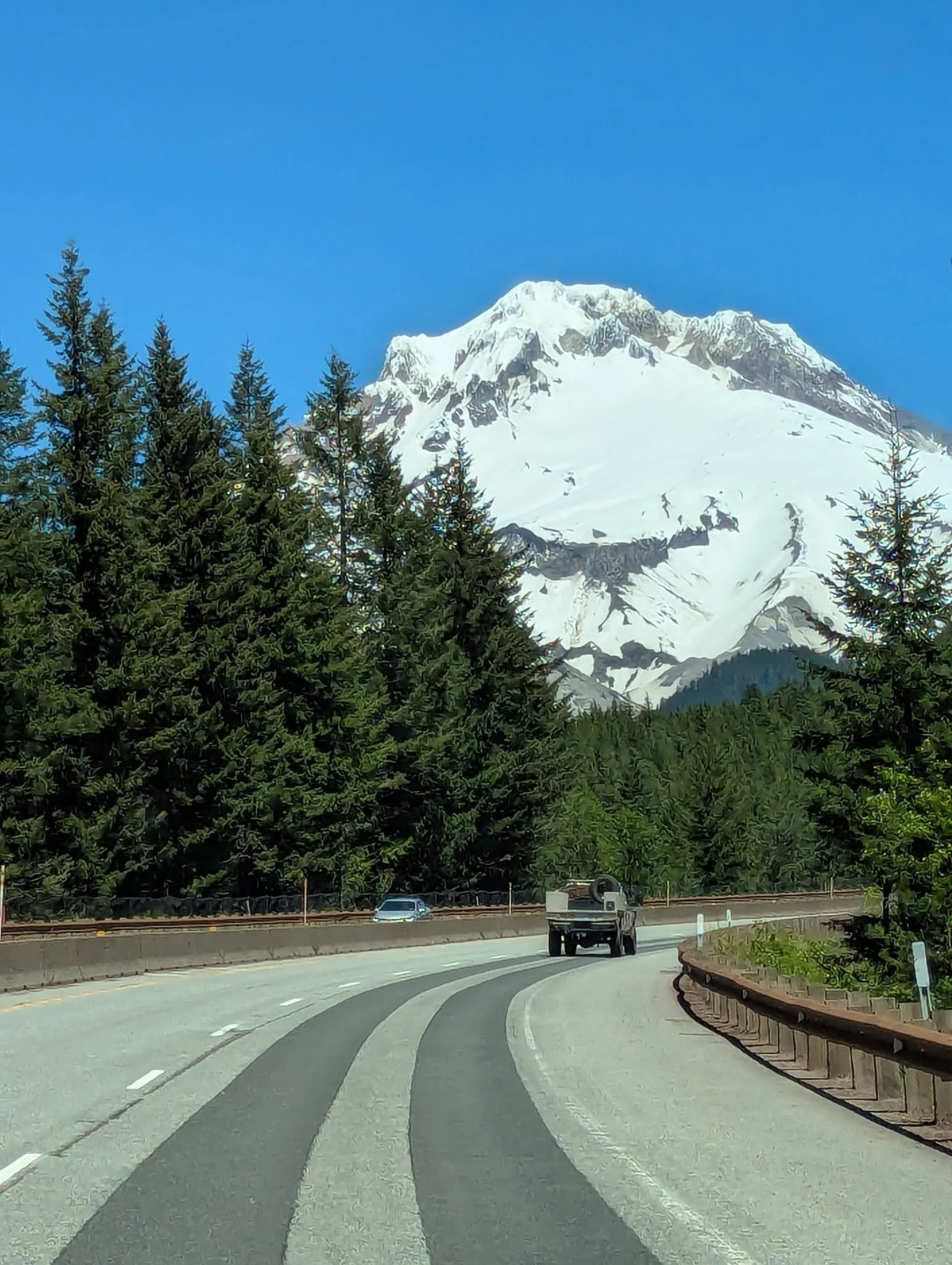 Snow-covered Mount Hood rising above an Oregon landscape beneath a clear blue sky.