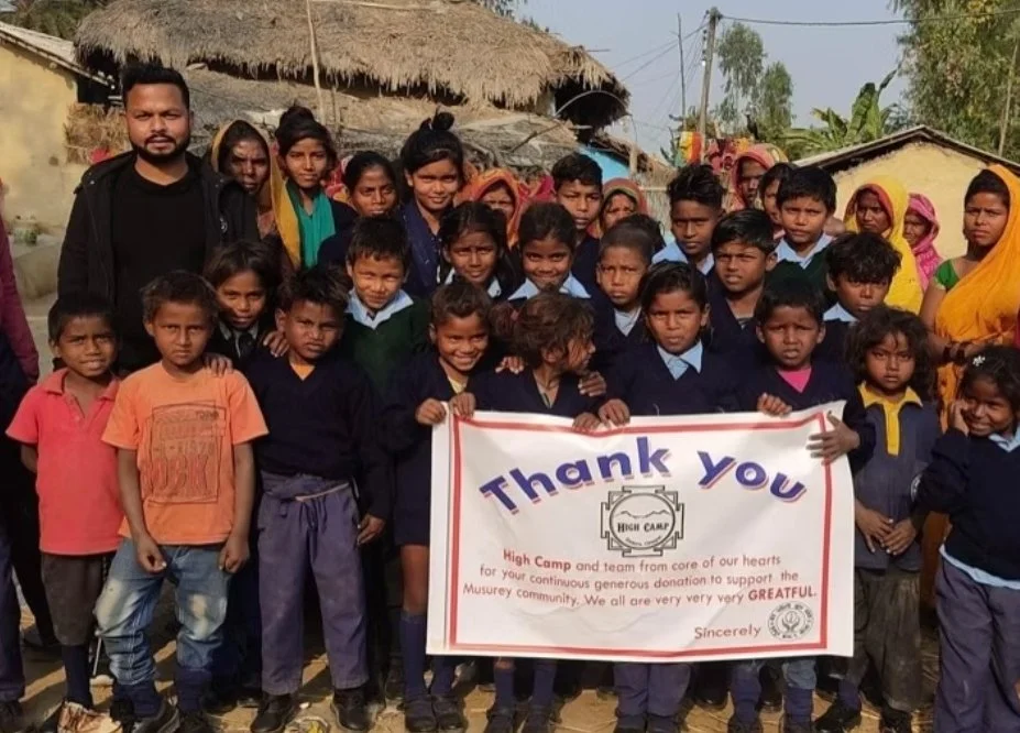Children and community members in Nepal gather with a banner thanking High Camp for its continued support and donations to the Musurey community.