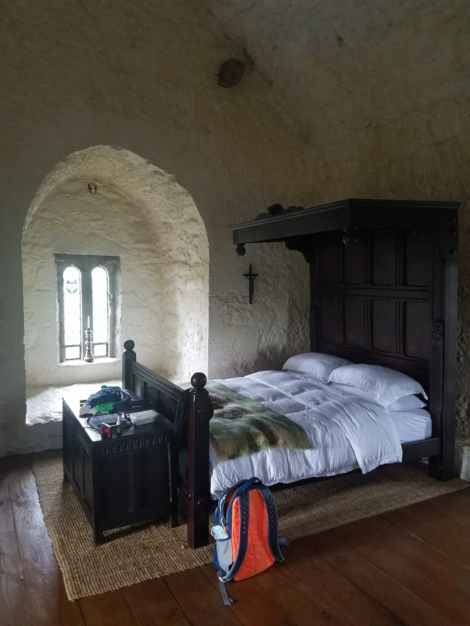 Period-style wooden bed beside a deeply recessed stone window inside Black Castle in Ireland.