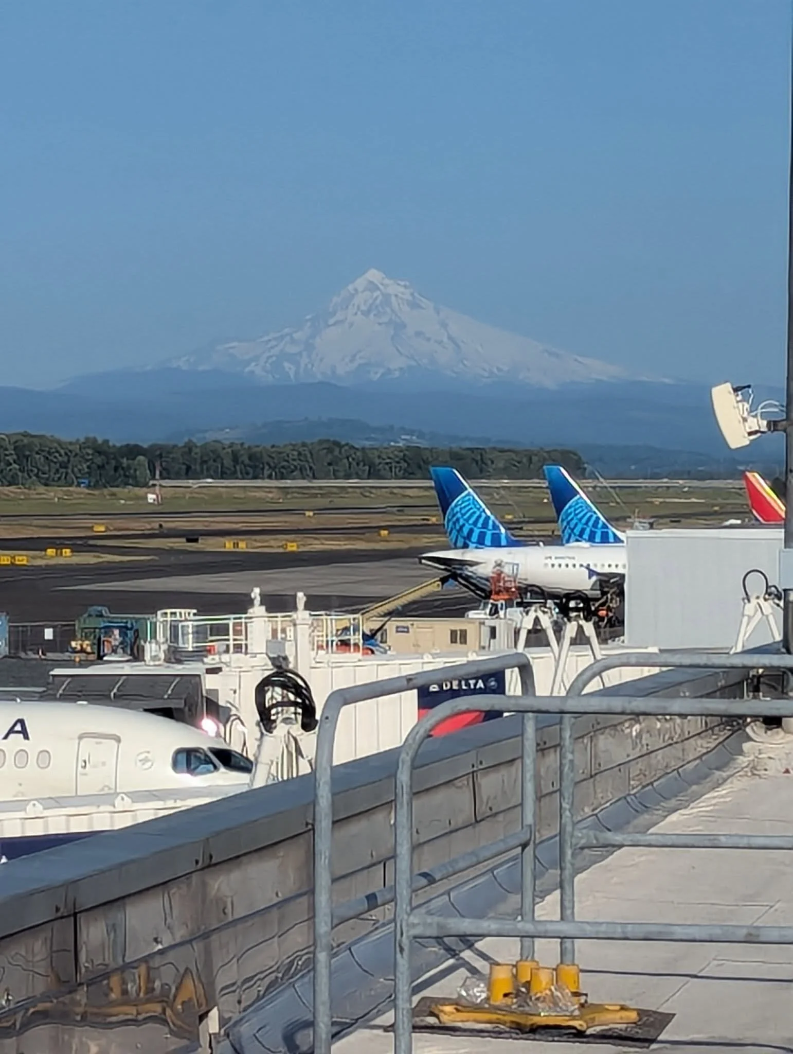 Snow-covered Mount Hood rising beyond parked commercial aircraft at Portland International Airport at the end of an Oregon road trip.