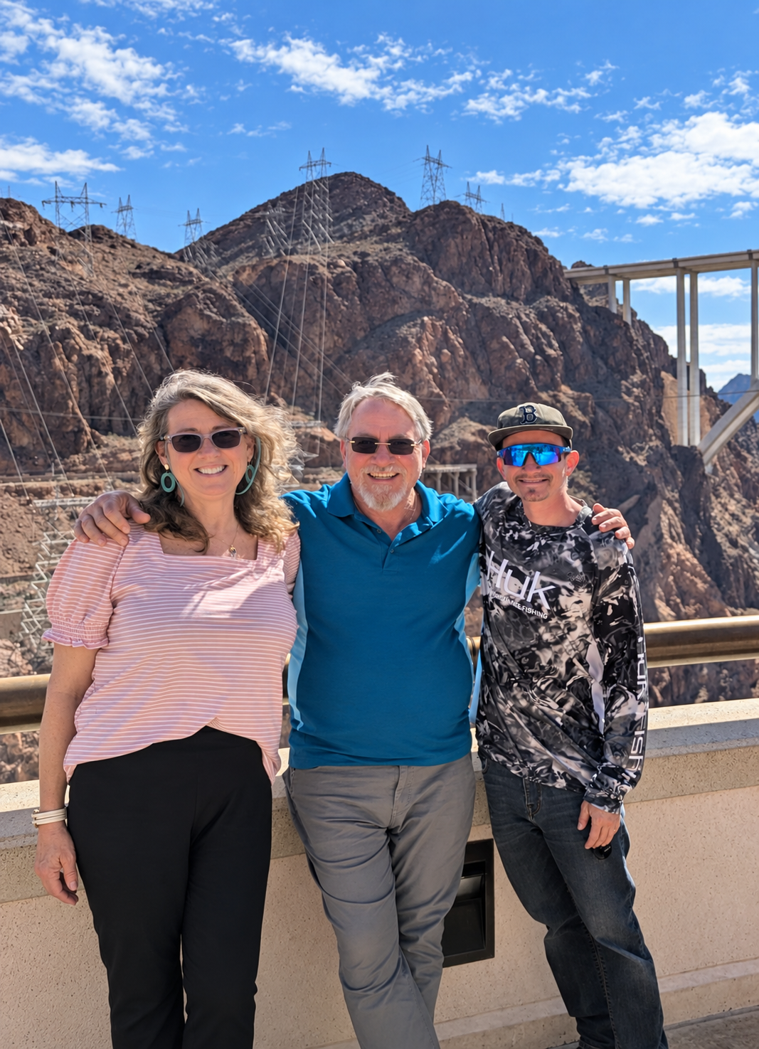 Gina, Brian and their son together at Hoover Dam with the canyon and memorial bridge behind them.
