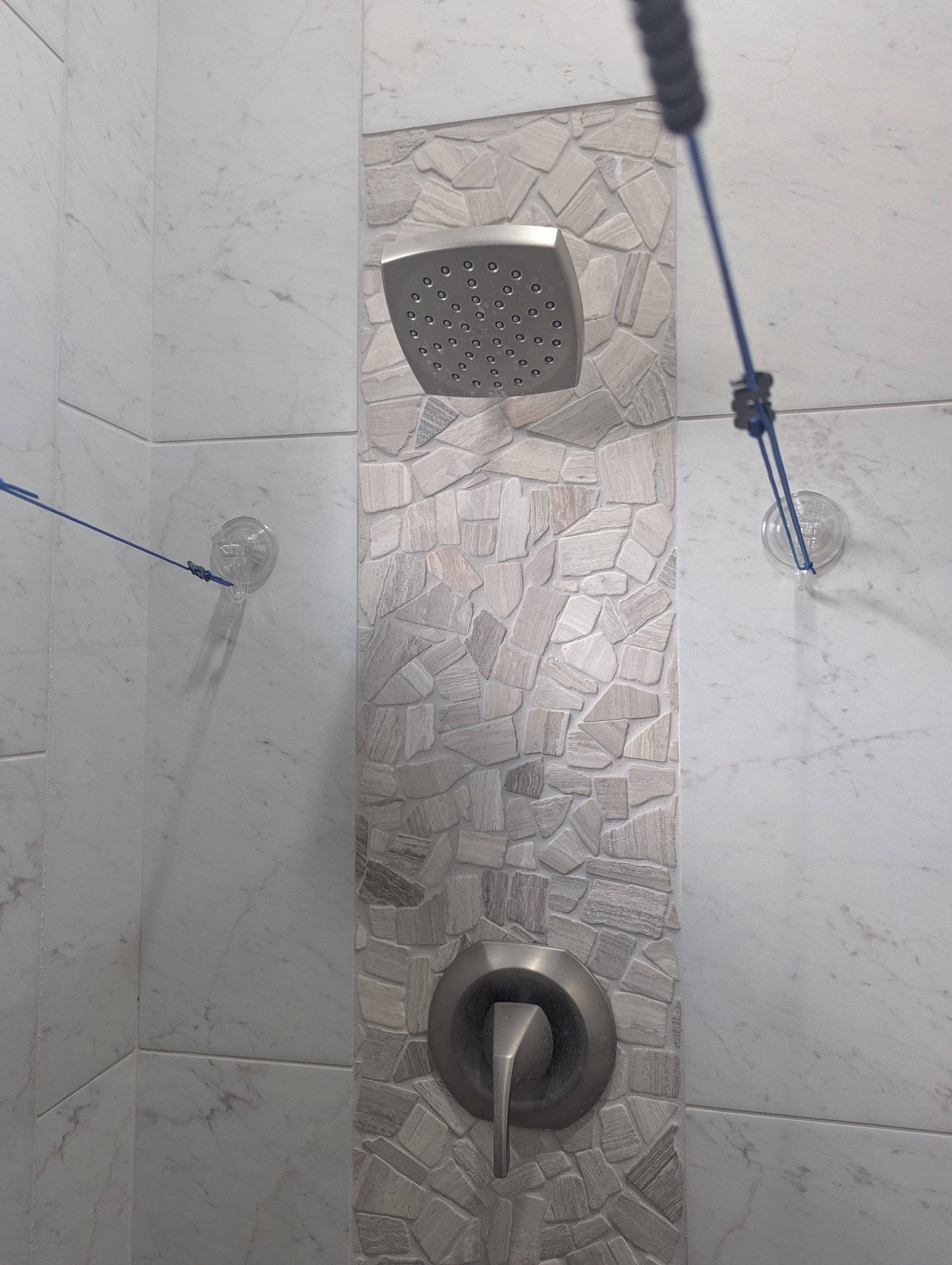 Two suction-cup hooks supporting tensioned portable clotheslines across a shower during a travel laundry test.