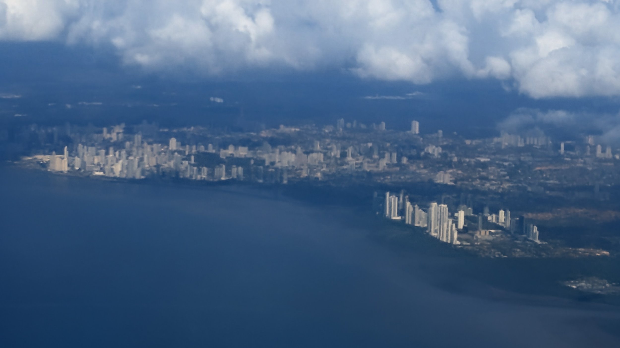 Aerial view of Panama City’s waterfront skyline beneath low clouds during the approach by air