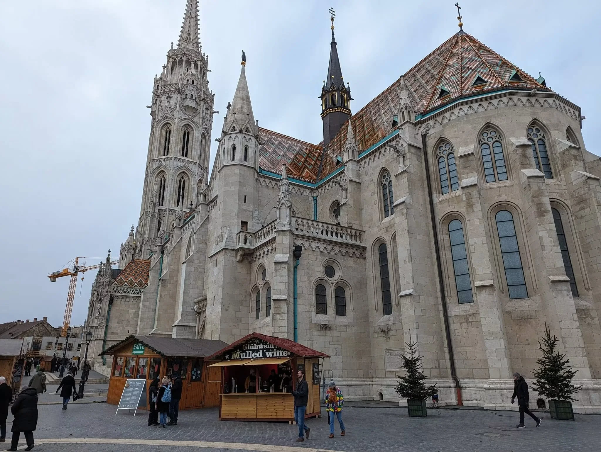 Matthias Church in Budapest's Castle District, with its colorful patterned roof and wooden mulled-wine stalls during December 2023.