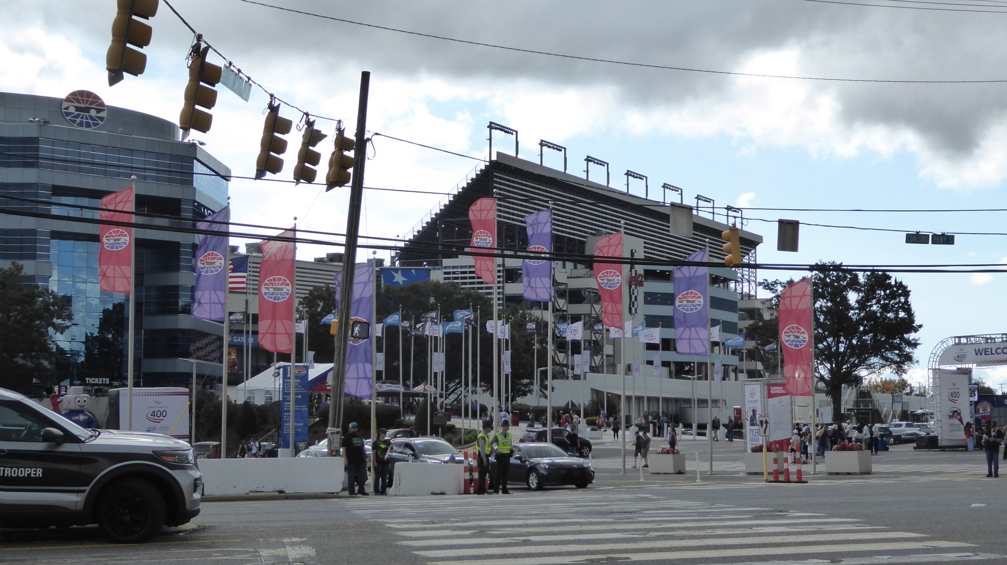 Exterior of Charlotte Motor Speedway with grandstands, pedestrian crossings, and surrounding race-day facilities.