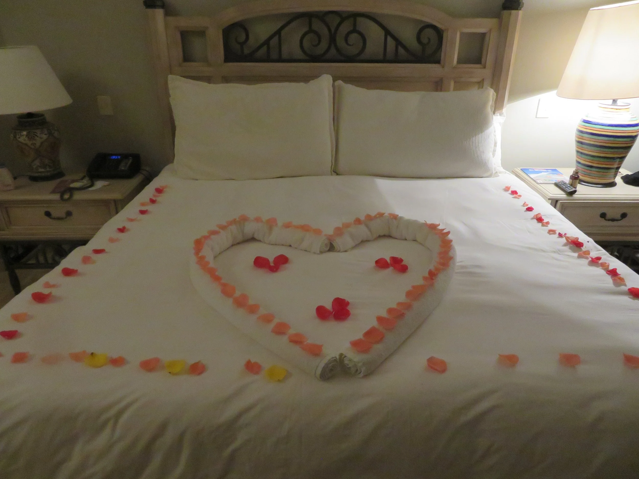 Honeymoon room at Sandos Cancun decorated with towel swans and colorful flower petals on the bed.