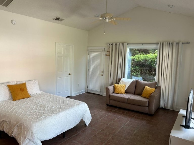 Interior of the Harrisburg Airbnb pool house showing the bed, sofa, television, and open studio layout.