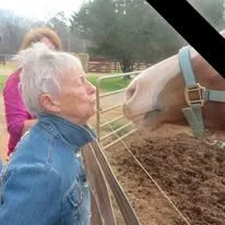 Sue leans over a corral fence to greet a horse during a family weekend at Southern Cross Ranch in Madison, Georgia.