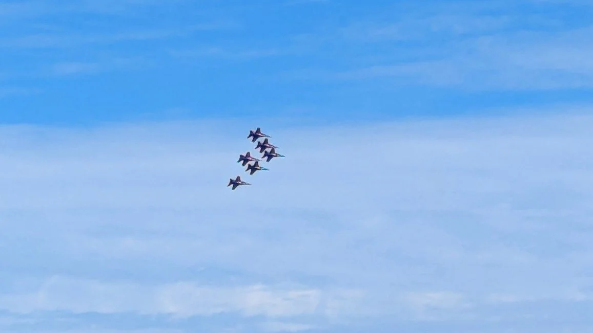Blue Angels jets flying in a tight formation against a blue sky during an air show over Jacksonville, Florida.