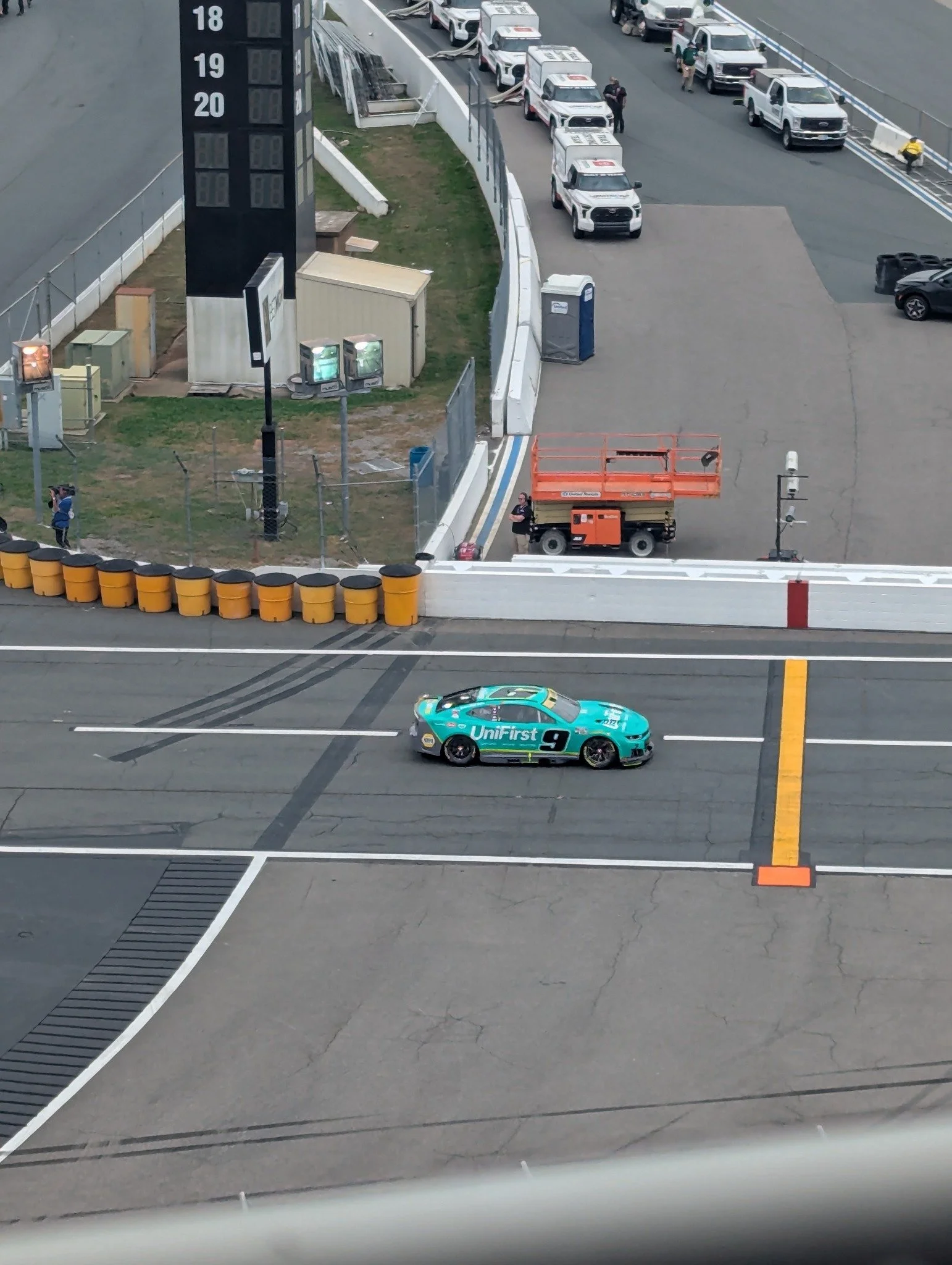 Zoomed Google Pixel 7 photograph of a turquoise NASCAR No. 9 race car on the Charlotte Motor Speedway racing surface.