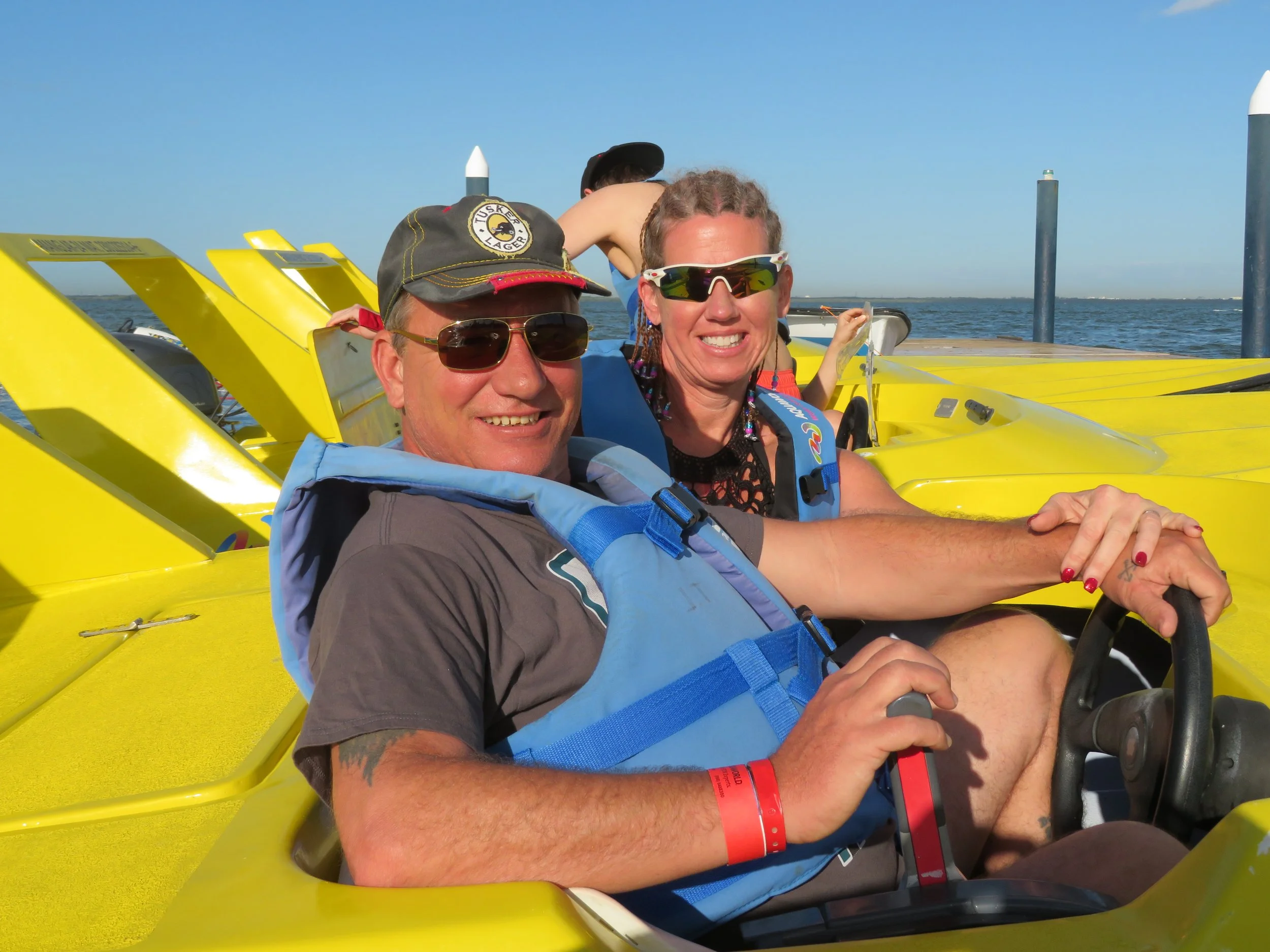 Brian and Gina wearing life jackets in a small yellow boat during an off-site adventure on their Cancun honeymoon.