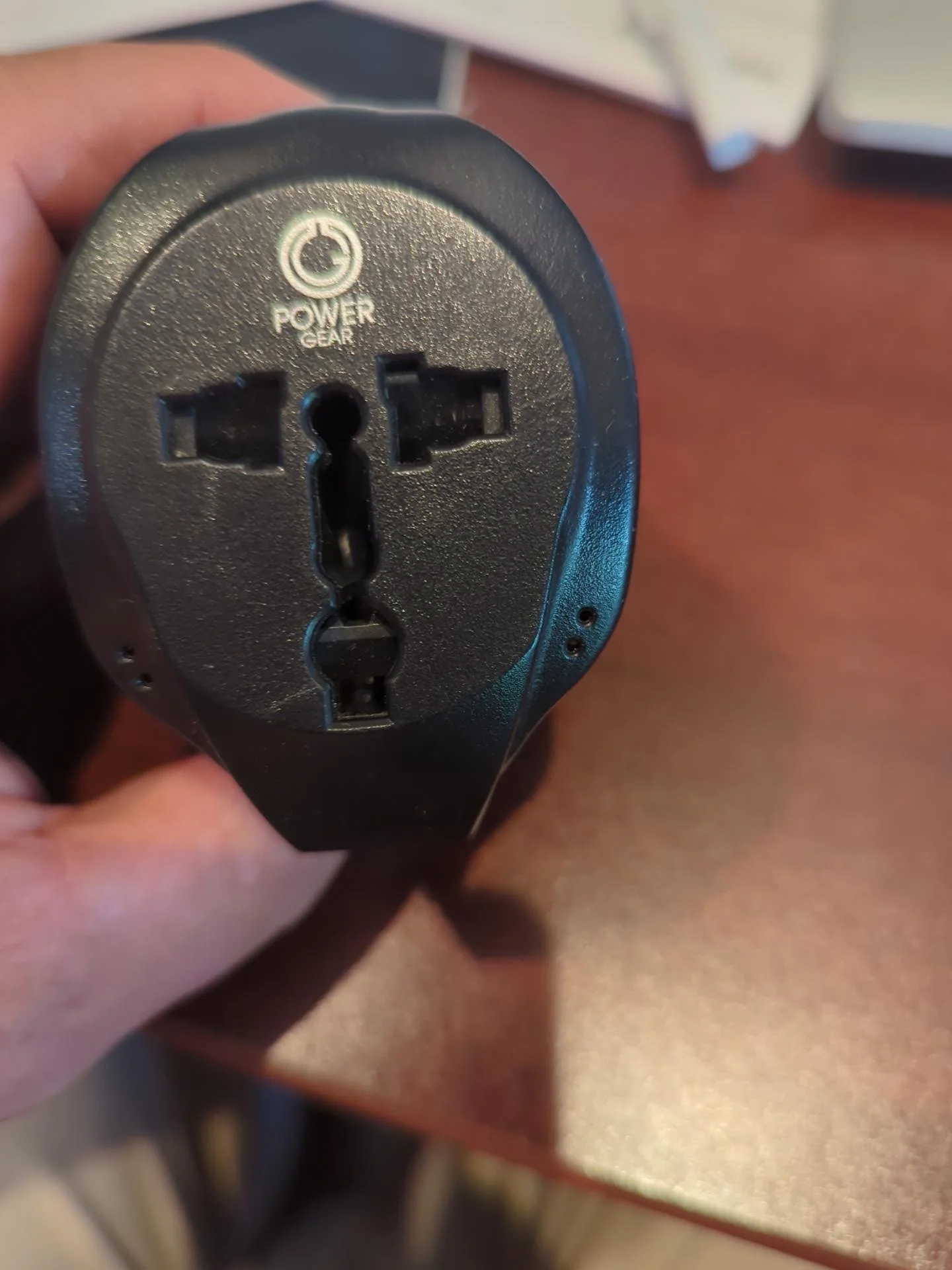 Compact universal travel adapter shown with different international plug configurations, carried as a backup to an international travel power strip.