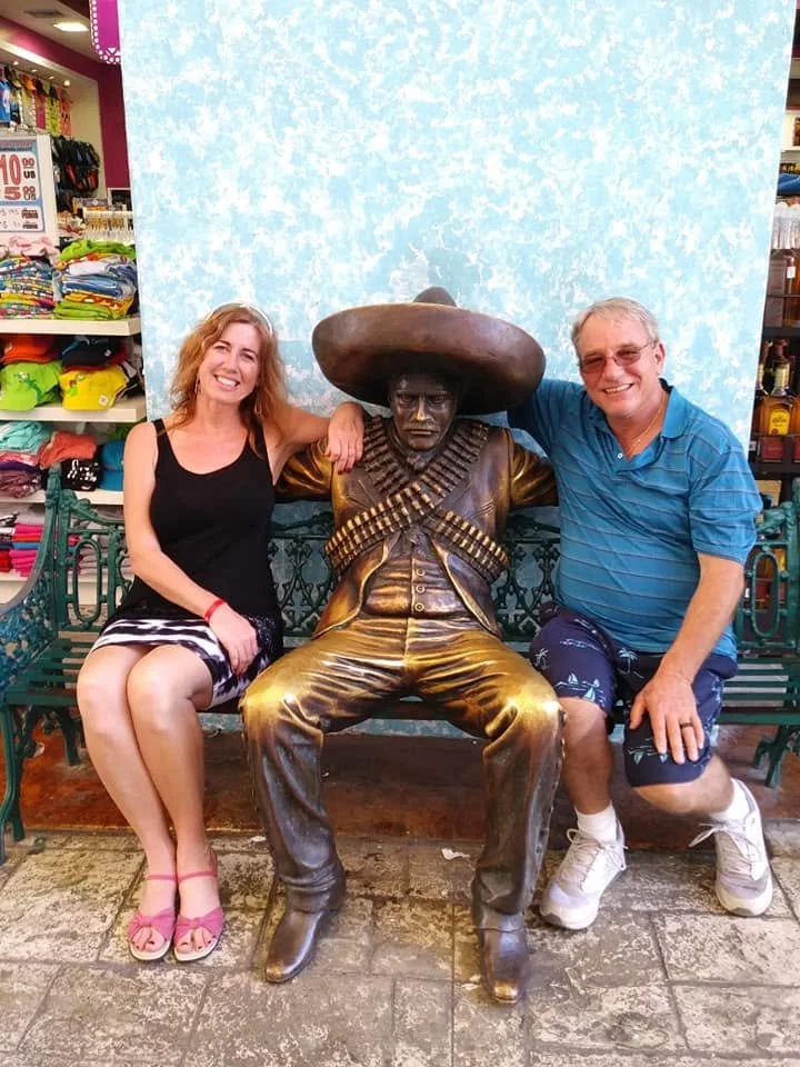 broze statue of mexican man with sombrero between brian and gina on a bench