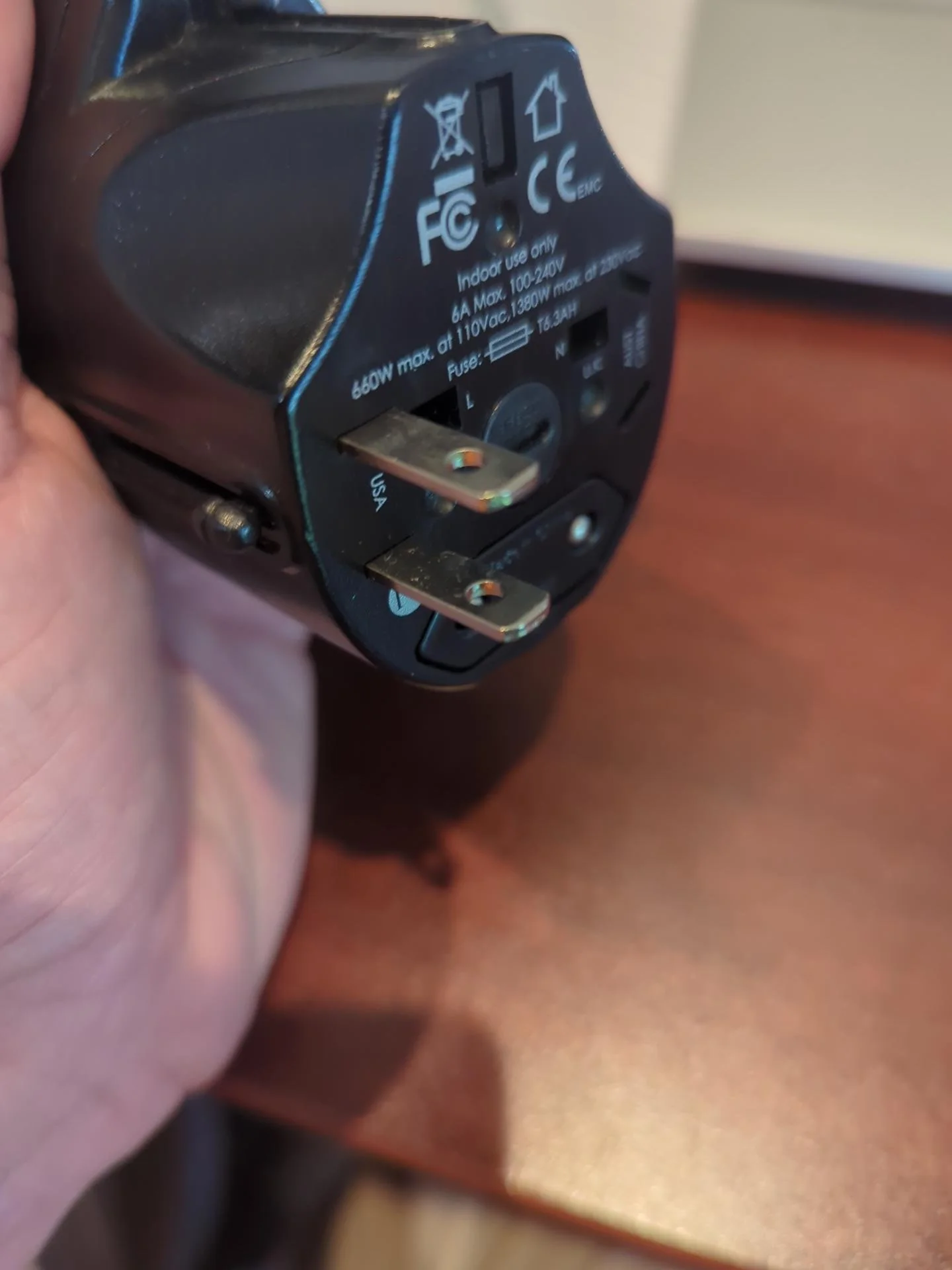 Compact universal travel adapter shown with different international plug configurations, carried as a backup to an international travel power strip.