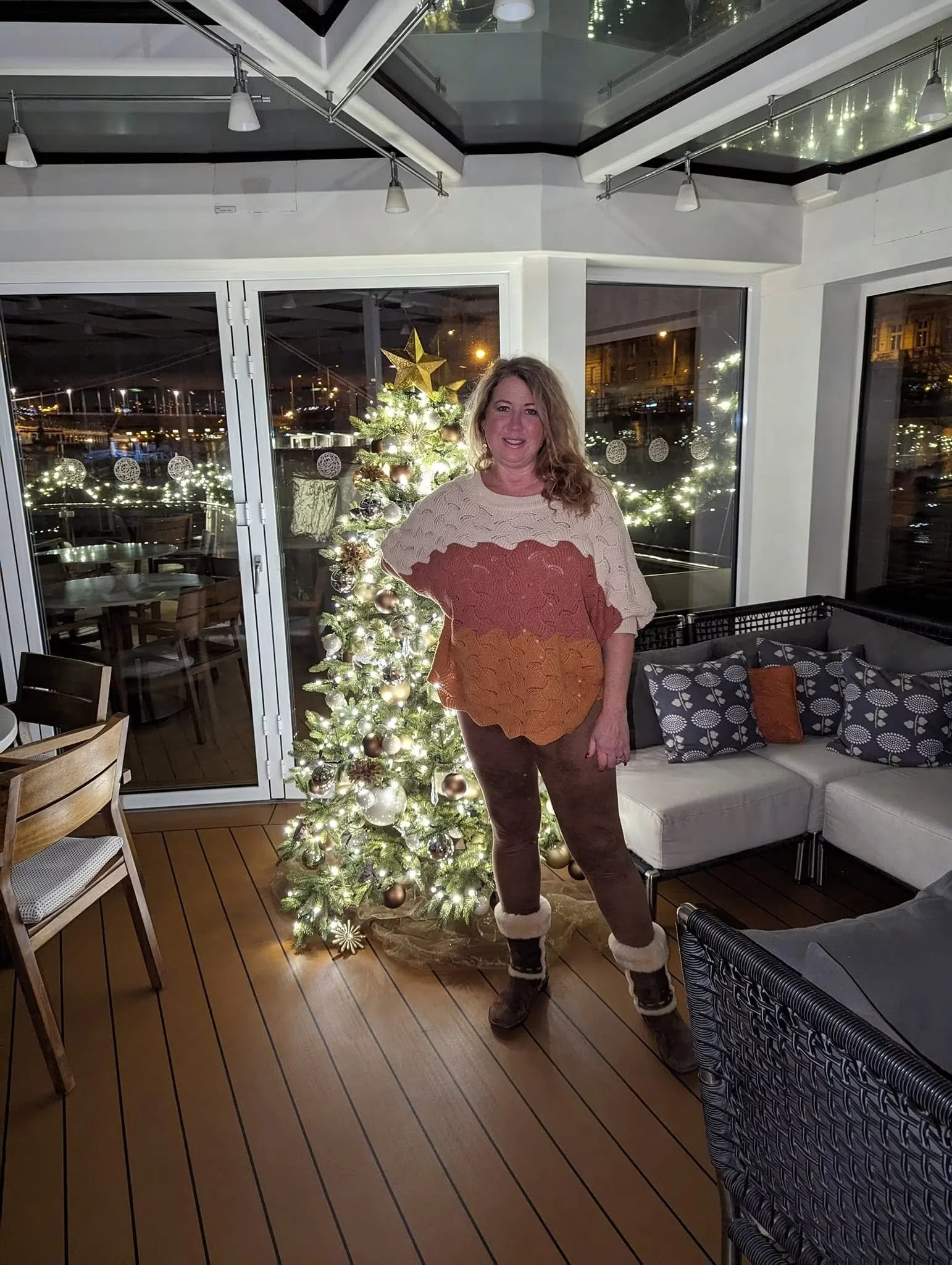 Gina standing beside a decorated Christmas tree in a cozy seating area aboard Viking Ingvi during a December 2023 Danube river cruise.