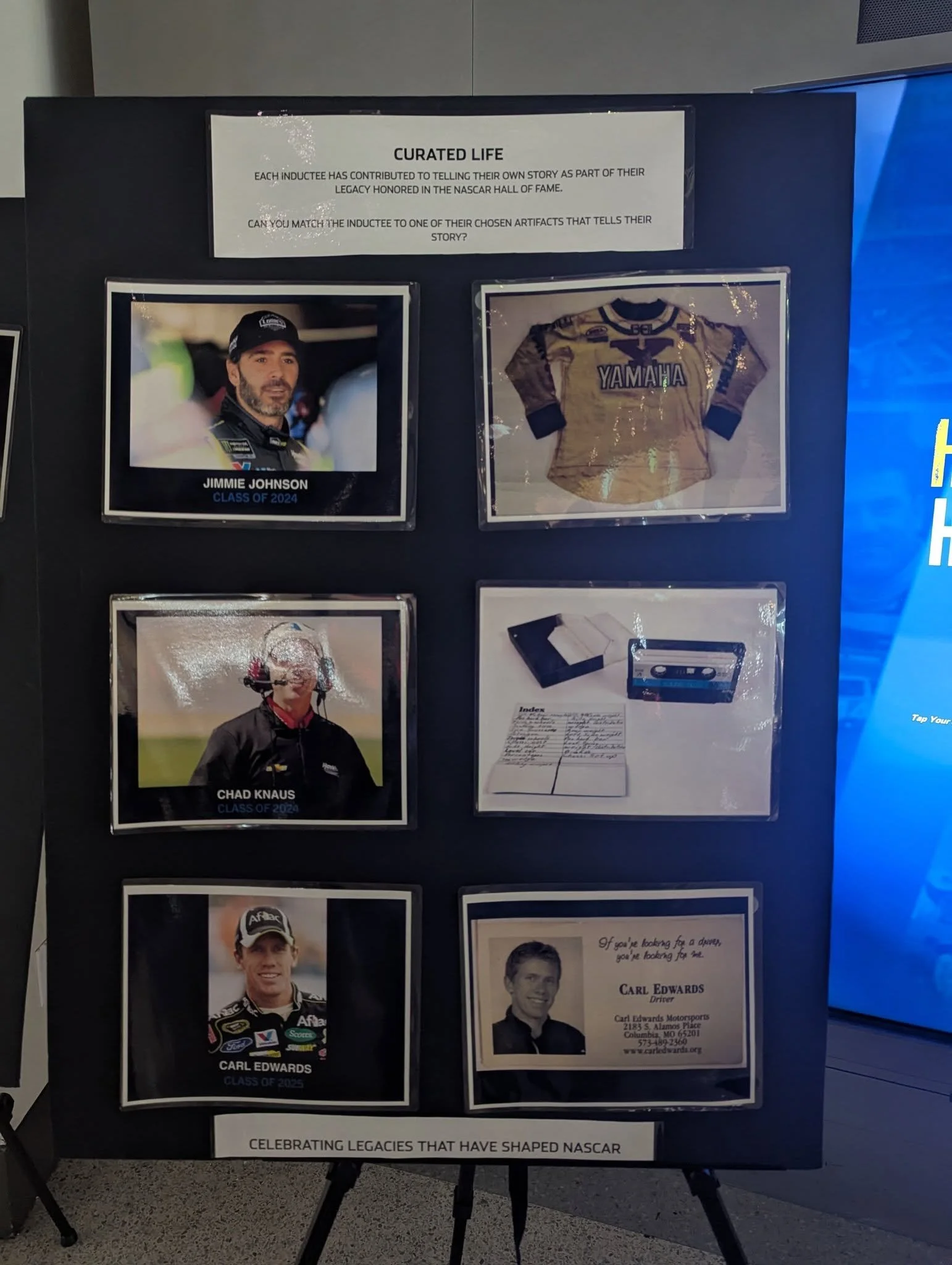 One of several Curated Life displays at the NASCAR Hall of Fame, showing Jimmie Johnson, Chad Knaus, and Carl Edwards alongside personal keepsakes chosen to tell their stories.