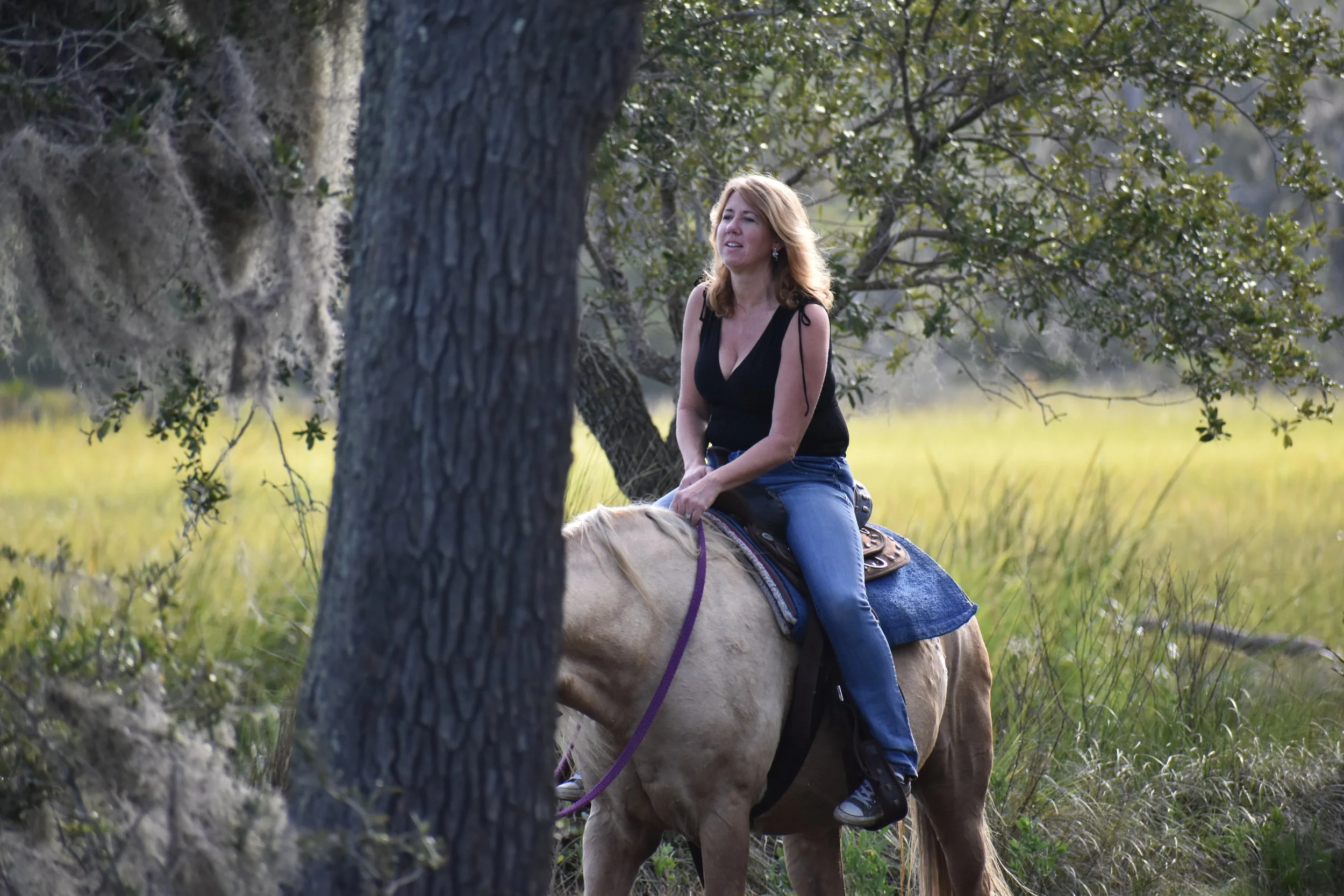 Gina riding a light-colored horse during a guided horseback excursion on Jekyll Island, Georgia