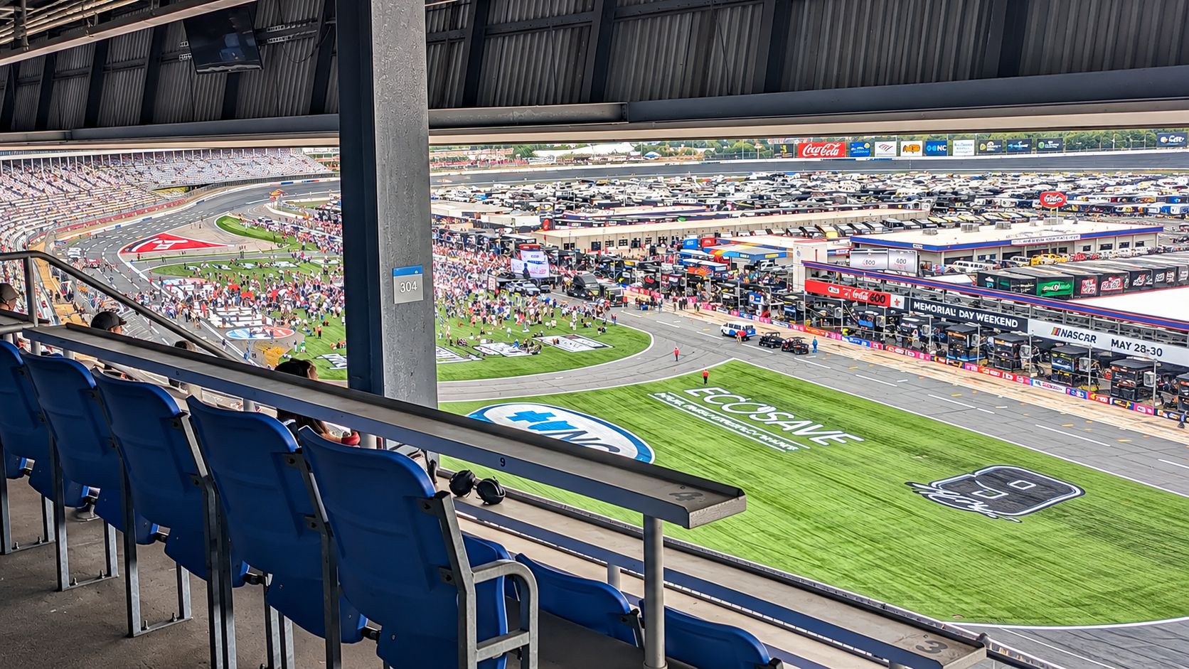 Covered Section 304 premium seating at Charlotte Motor Speedway, featuring blue stadium seats, individual tables, and overhead protection.