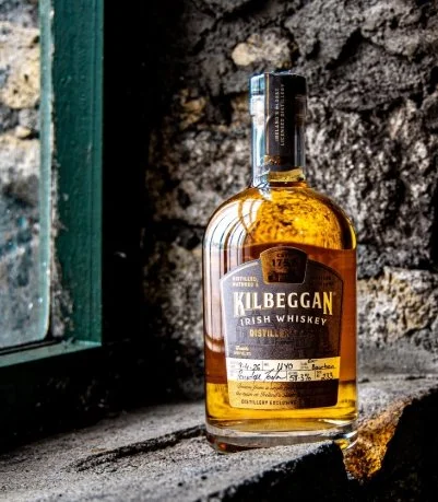 Bottle of Kilbeggan Irish whiskey displayed in a window after our distillery experience during an Ireland road trip.