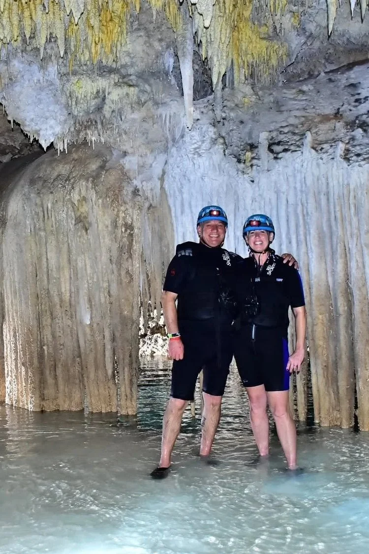 Brian and Gina wearing helmets and wetsuits while exploring a cenote near Cancún, Mexico.